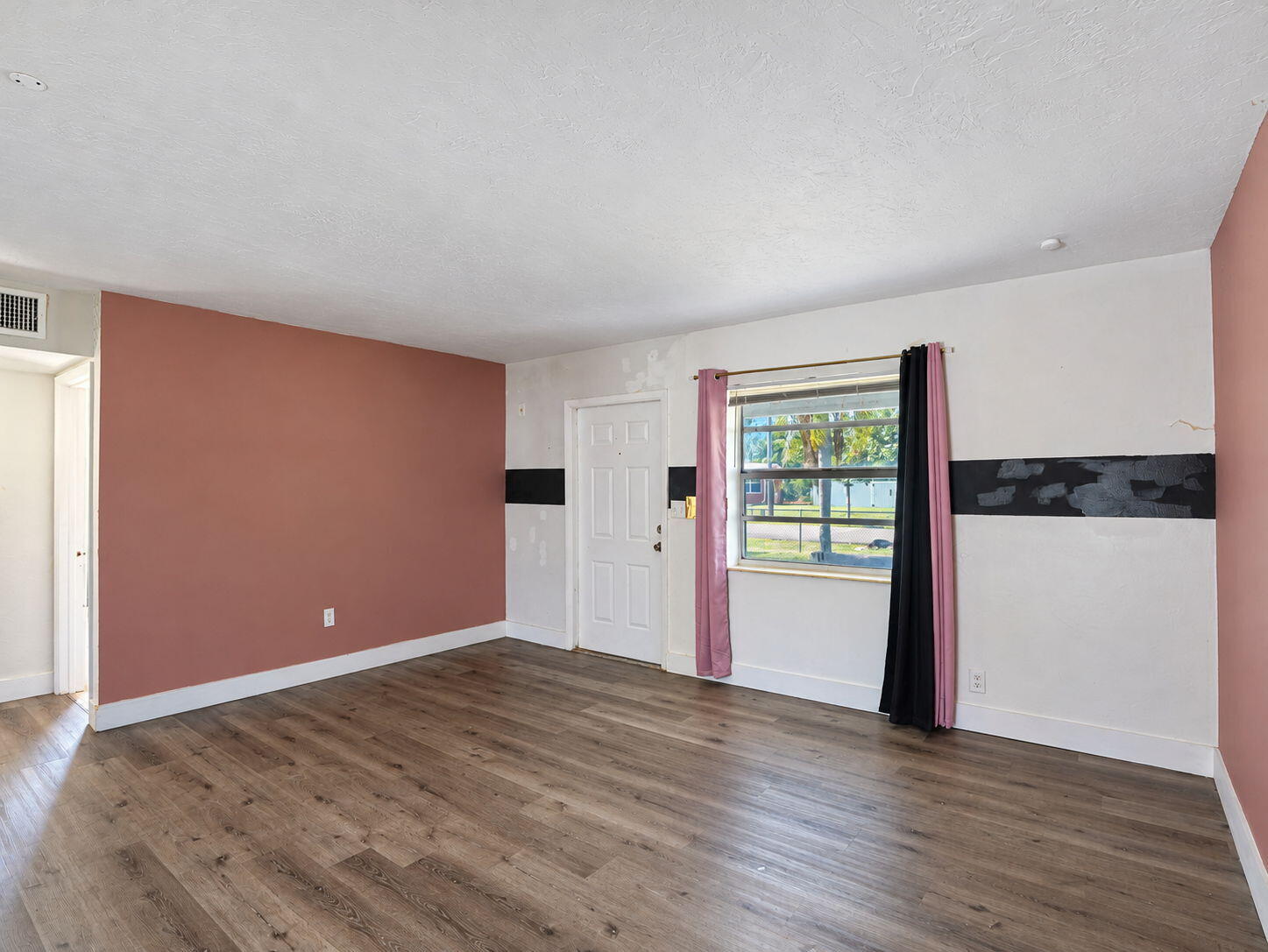 Living Room featuring wood-finish flooring, floor-to-ceiling mirrored wall paneling