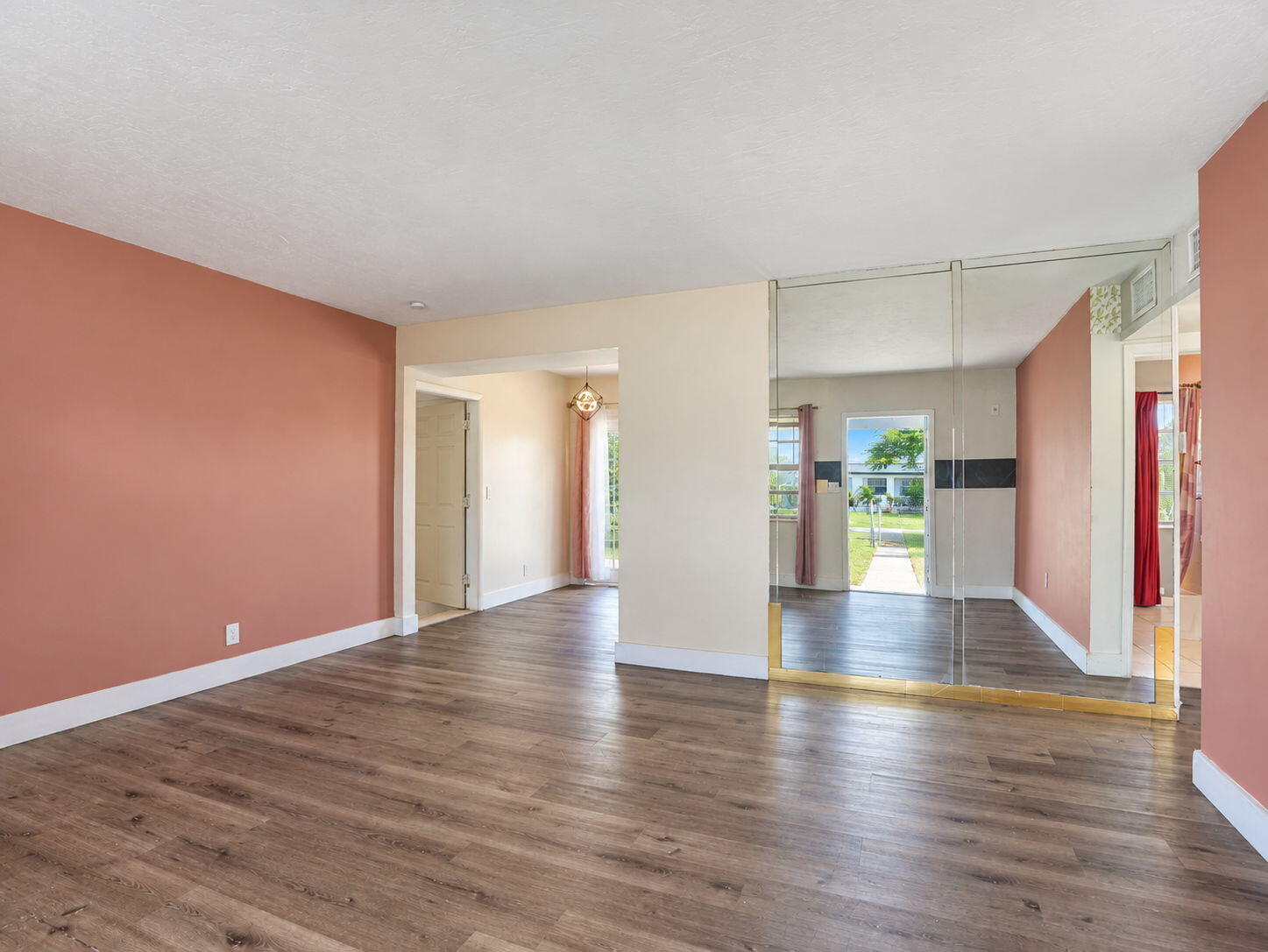 Living Room featuring wood-finish flooring, floor-to-ceiling mirrored wall paneling