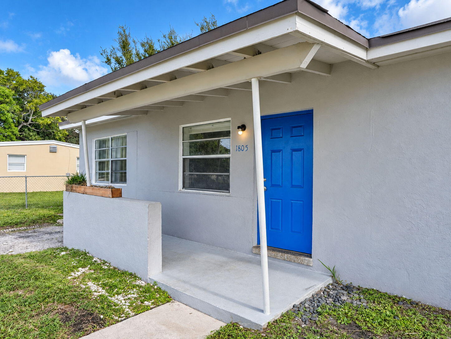 Exterior featuring a stucco facade, covered porch with a concrete stoop, single-panel blue front door