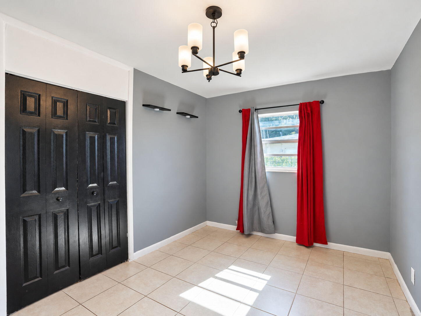 Neutral-toned tile flooring, four-panel black bi-fold closet doors, multi-arm chandelier with frosted glass shades, and two integrated wall-mounted accent shelves