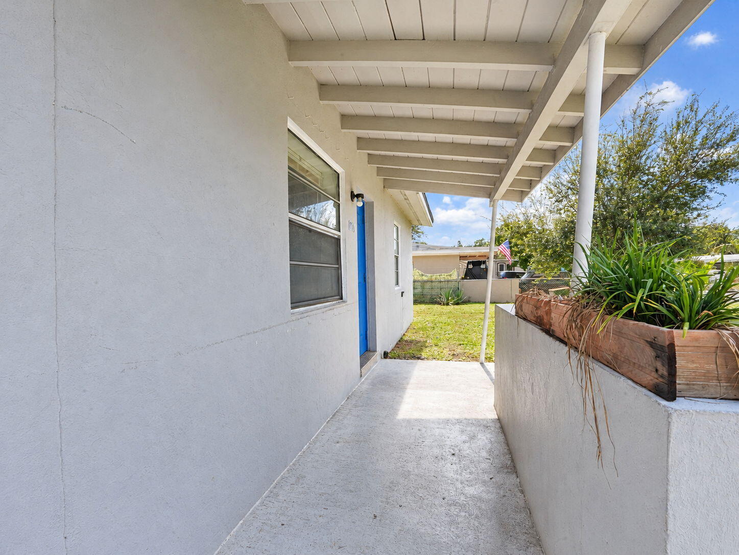 Covered exterior porch featuring a concrete floor, painted stucco siding, and a built-in stucco planter