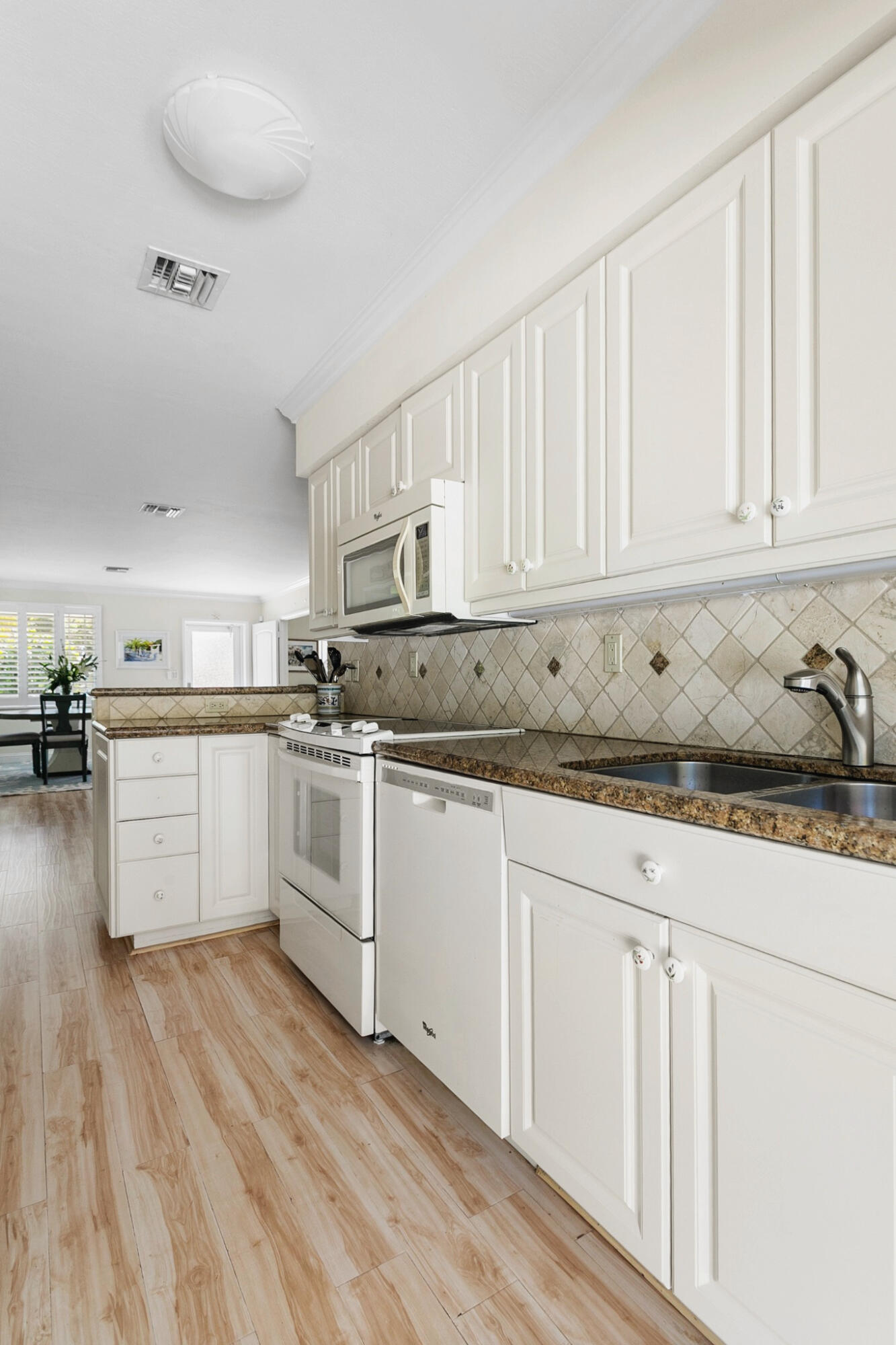 Kitchen featuring neutral wood cabinetry, stone-finish countertops, diagonal-set tile backsplash, wood-finish flooring, and integrated white appliances