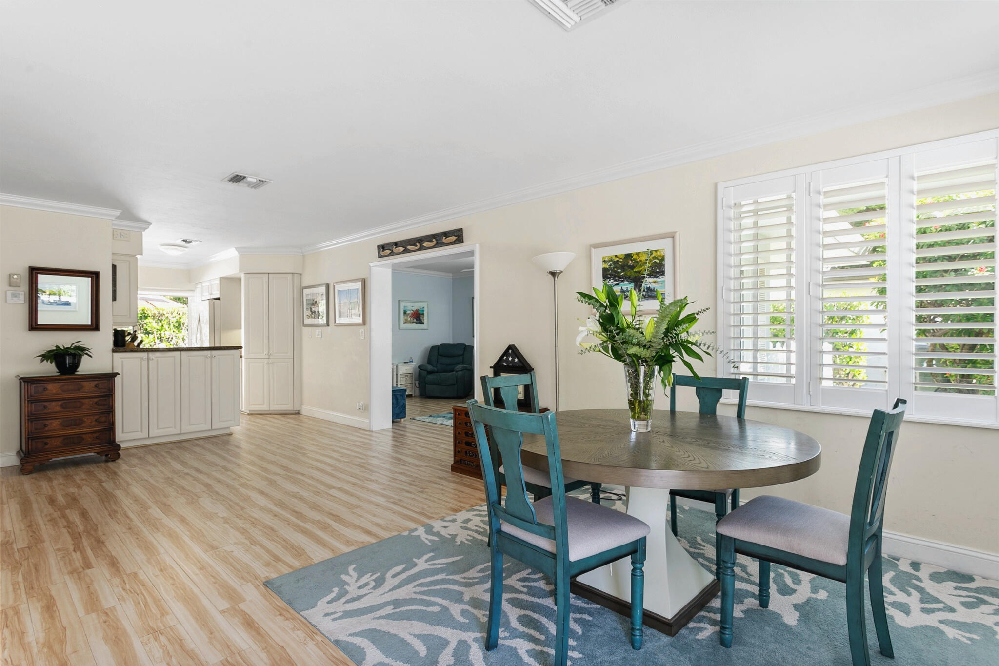 Open-concept interior featuring light-toned wood-finish flooring, plantation shutters and crown molding