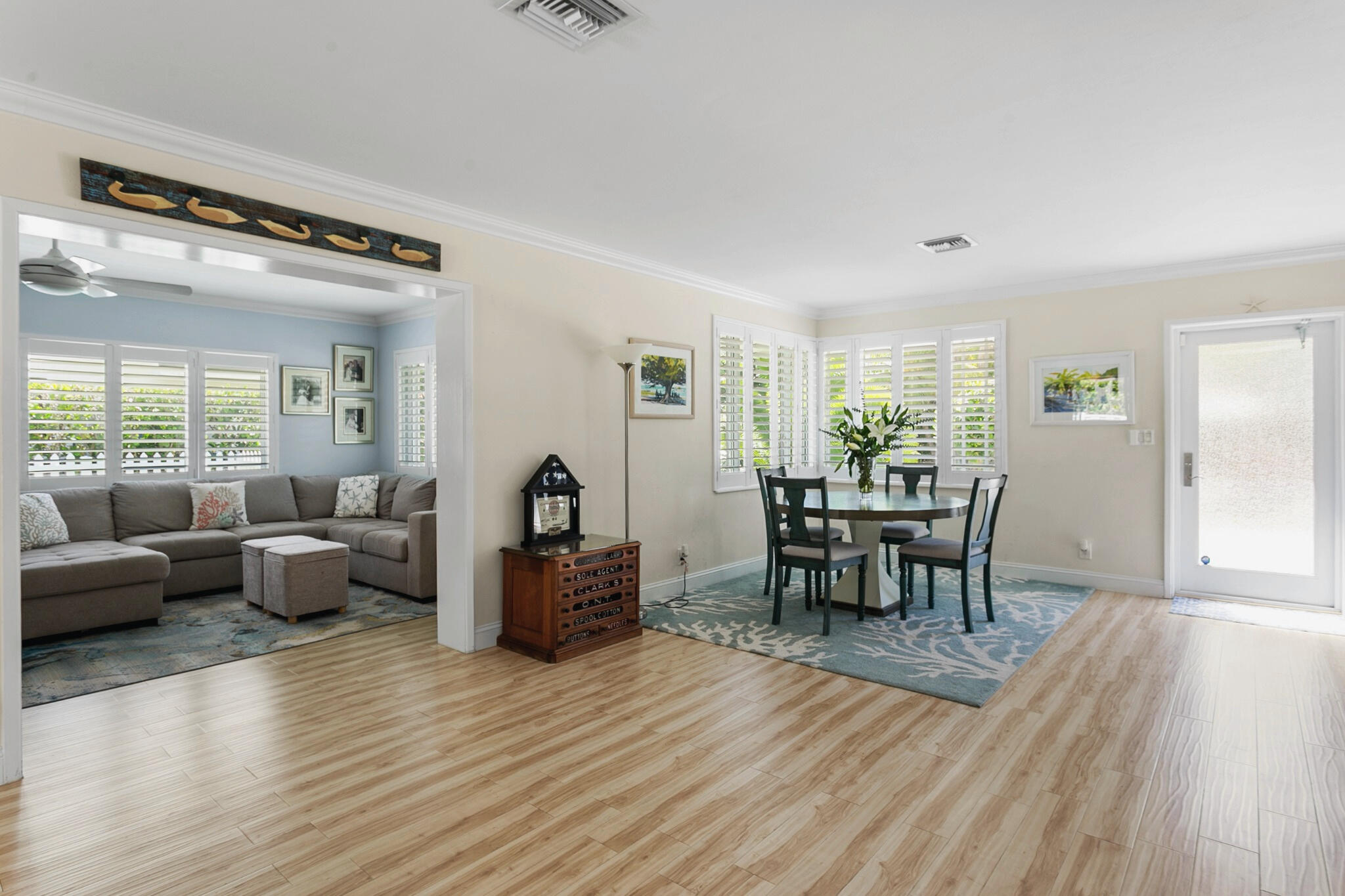 Open-concept living space featuring wood-finish flooring, plantation shutters, crown molding, and a partial wall partition