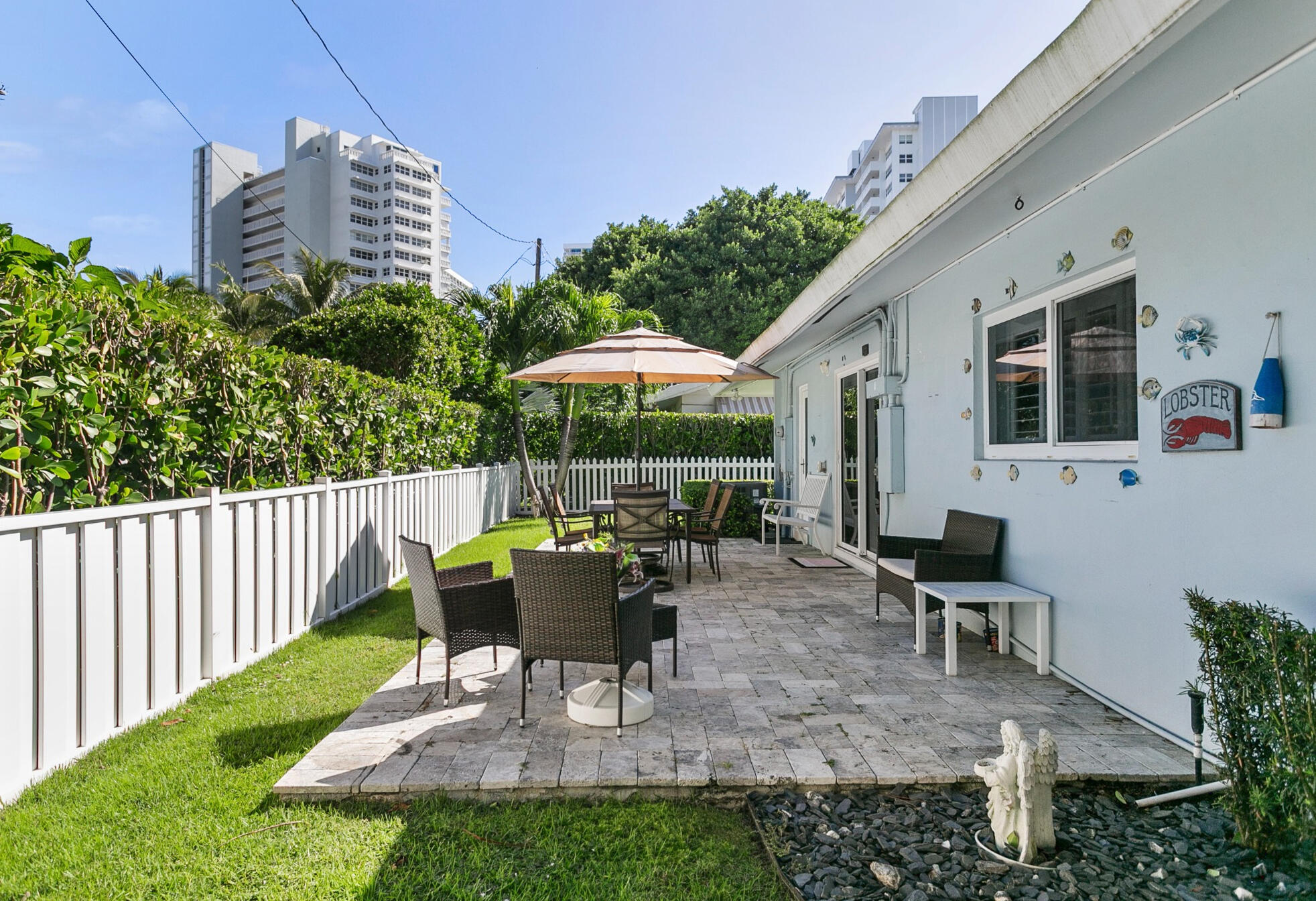 Rear patio featuring natural stone pavers, green space and bordered by a privacy fence