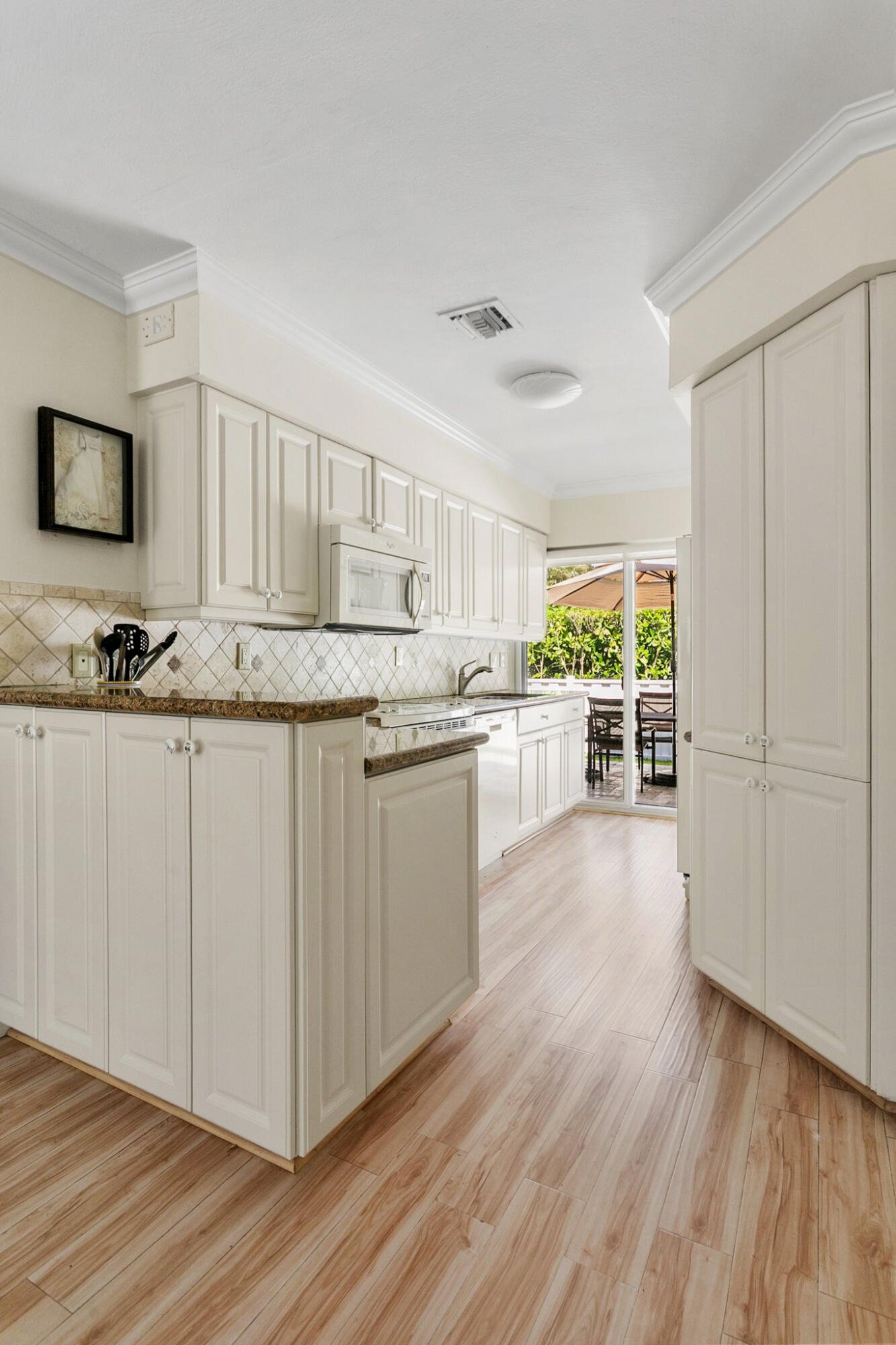 Kitchen featuring off-white cabinetry, stone-finish countertops, diagonal tile backsplash, and light wood-finish flooring