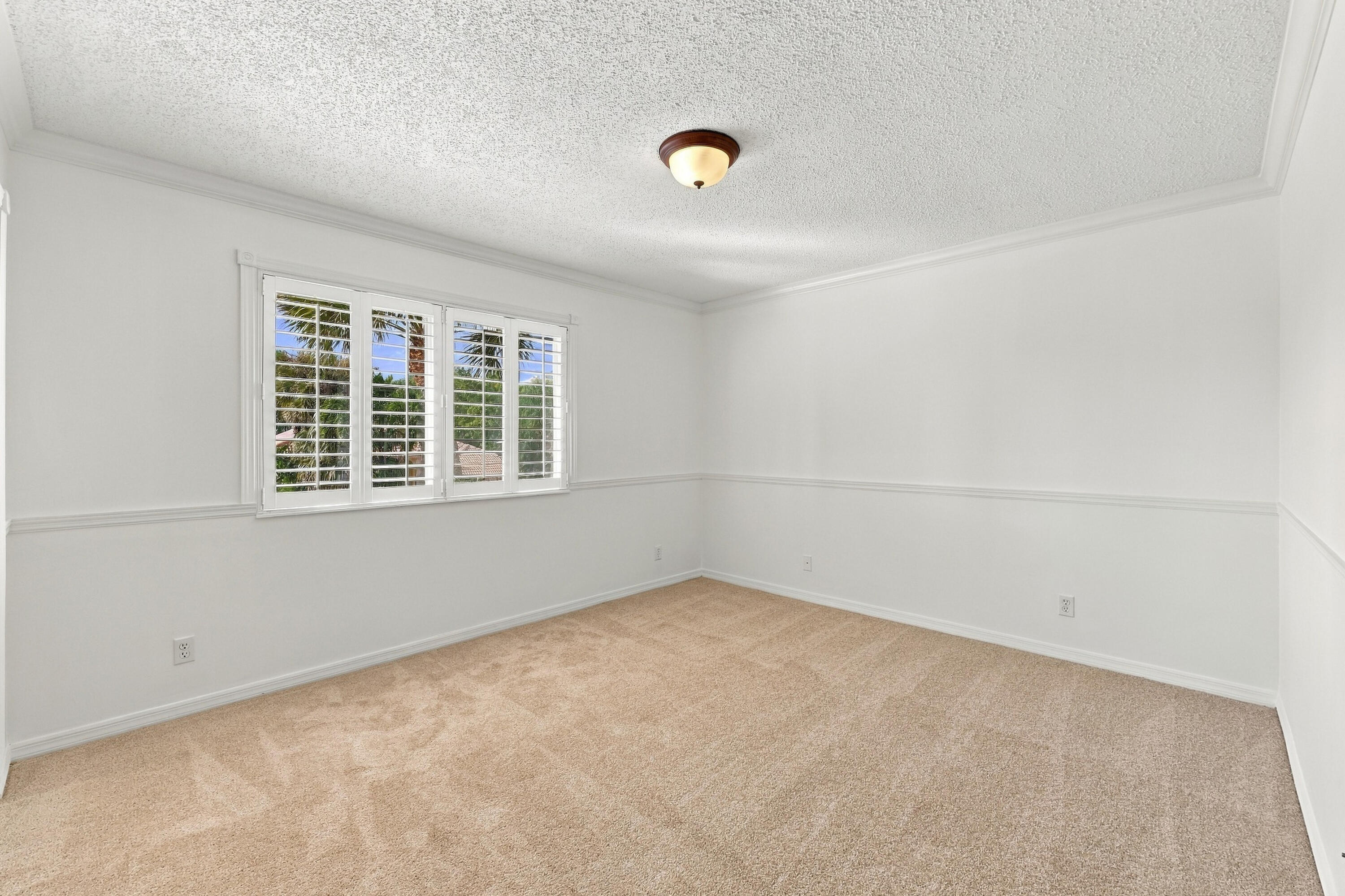 A generously sized bedroom featuring plush carpeting, neutral finishes, and ample natural light, creating a comfortable and welcoming space.