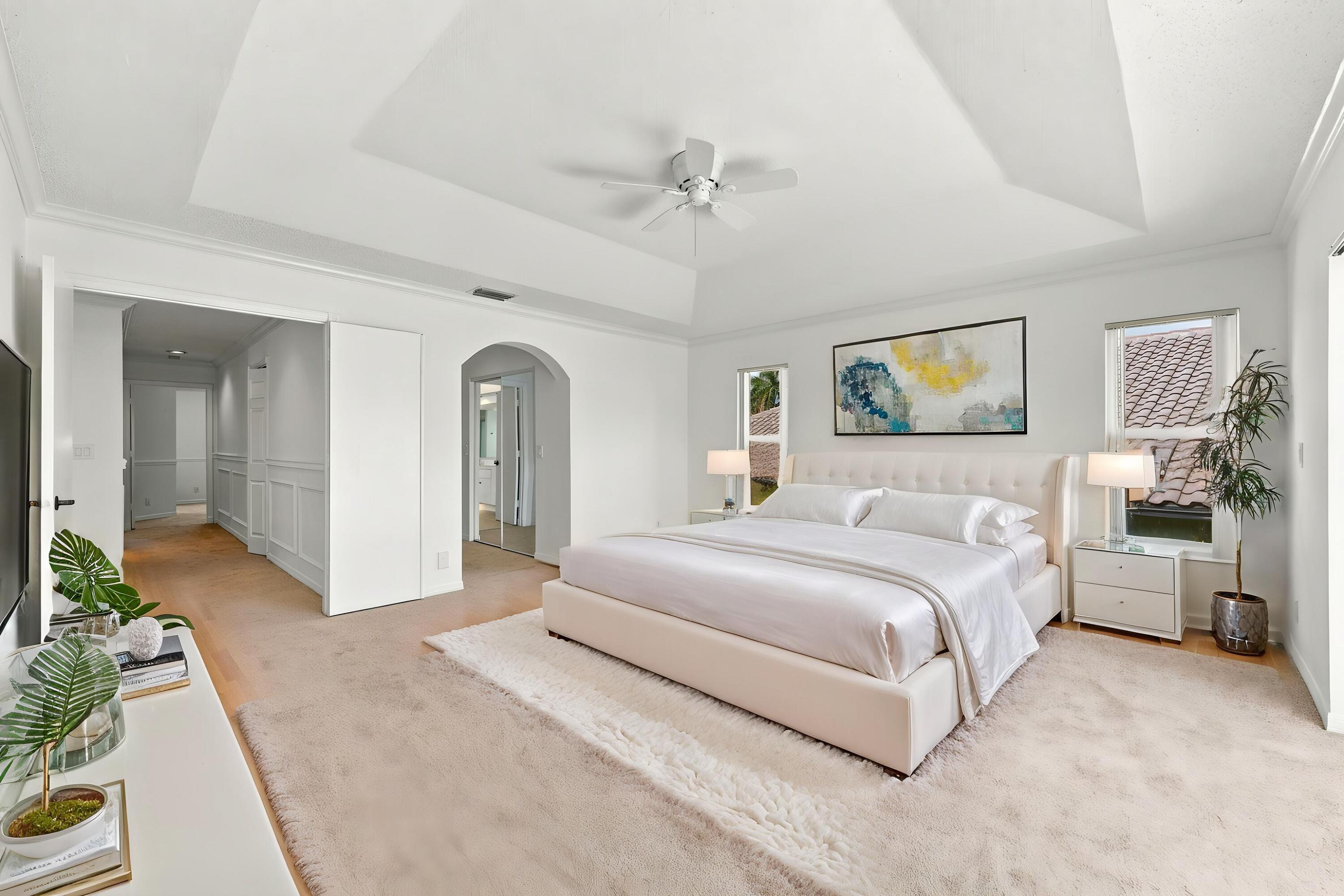 An impressive primary bedroom featuring a decorative tray ceiling, generous proportions, and a private entrance to the adjoining bathroom and dressing areas.