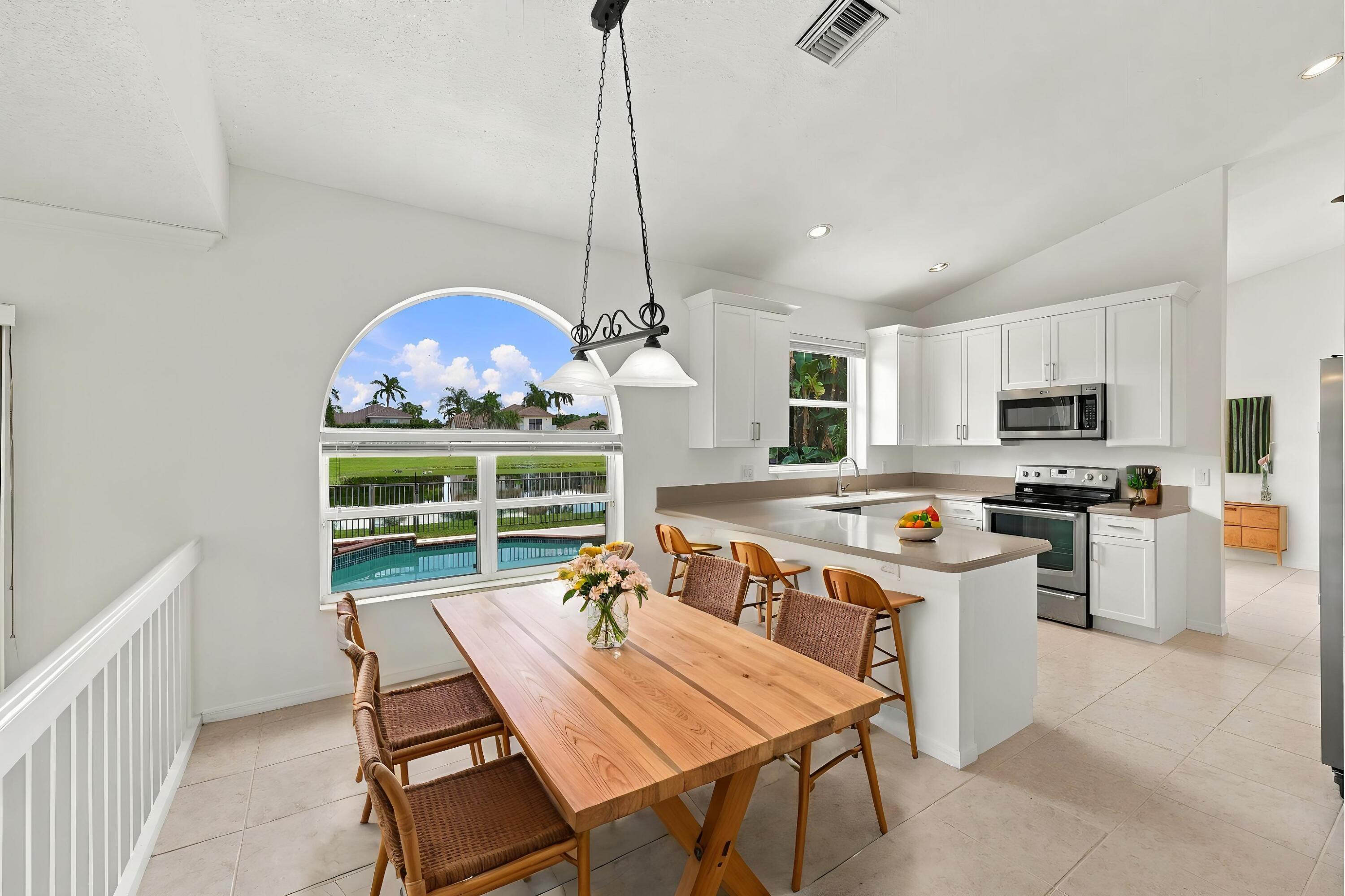Enjoy picturesque views of the surrounding greenery from the charming breakfast nook, complete with an oversized arched window, vaulted ceilings, and decorative lighting.