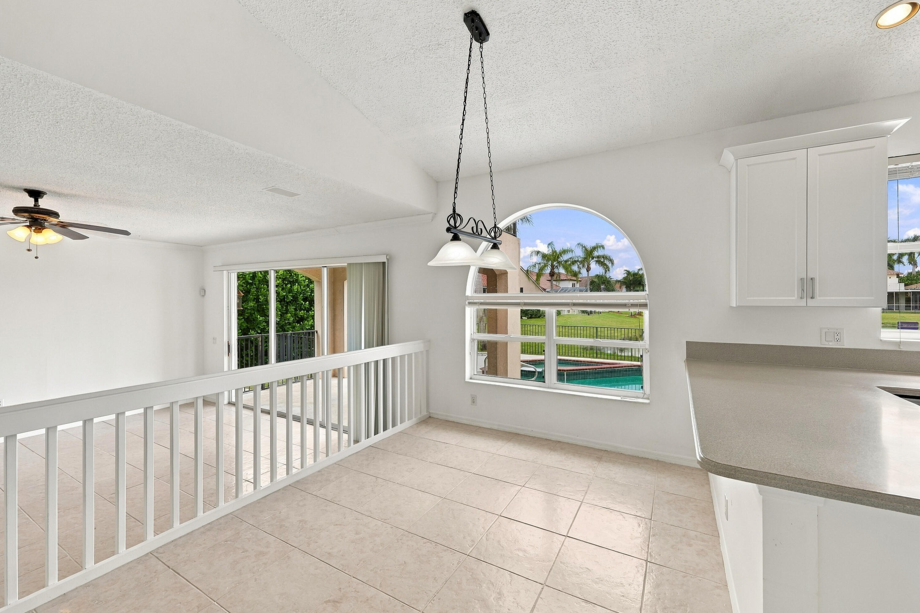 A wonderful setting for casual dining, this breakfast nook features an oversized arched window, decorative pendant lighting, and an open connection to the adjacent family room.