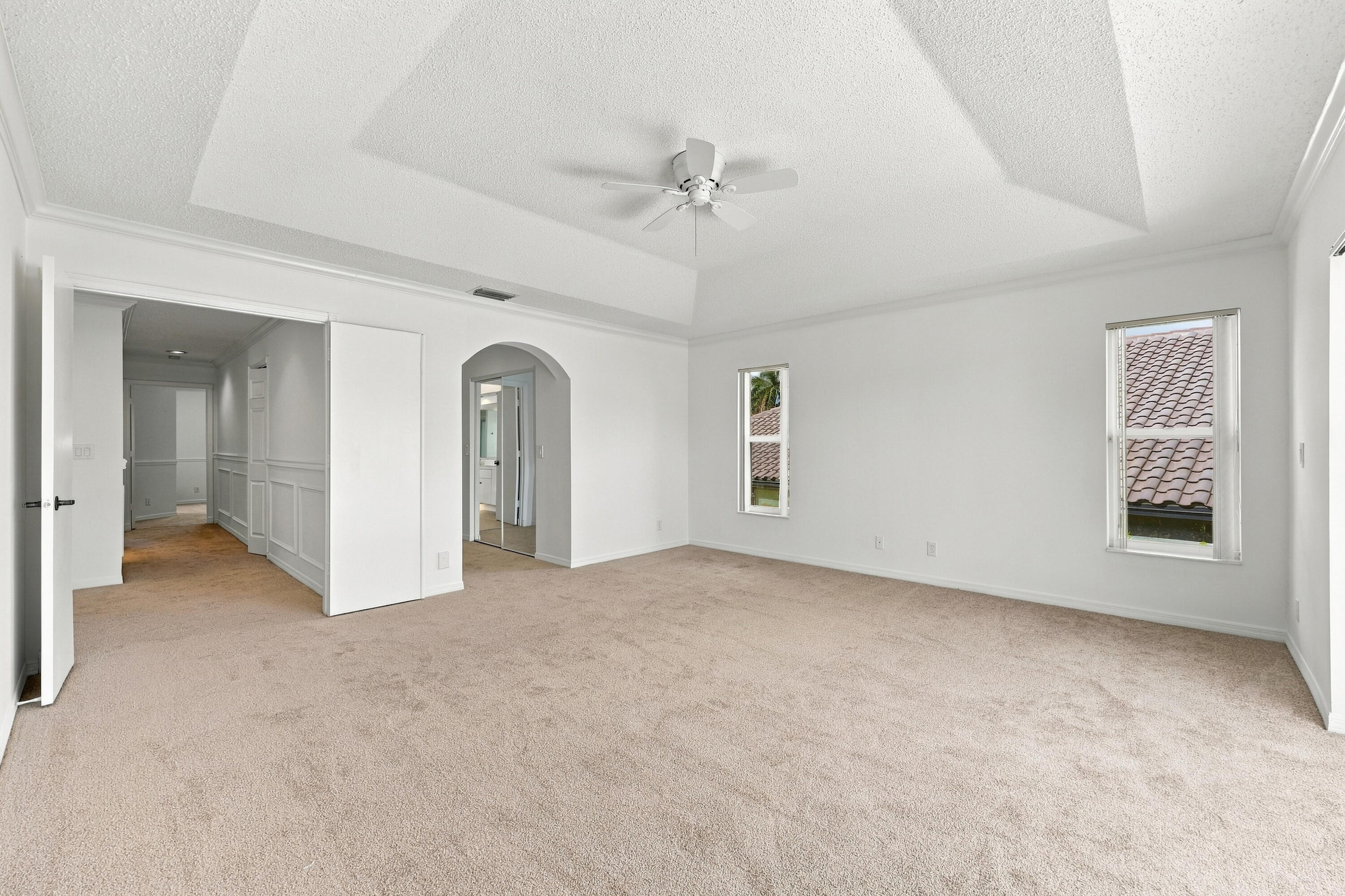 An impressive primary bedroom featuring a decorative tray ceiling, generous proportions, and a private entrance to the adjoining bathroom and dressing areas.