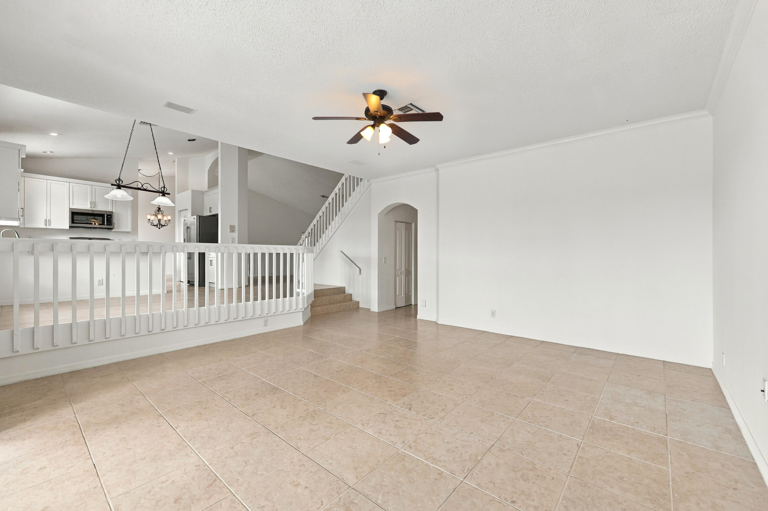 The generous formal living room offers soaring ceilings, an elegant chandelier, and an open design overlooking the home's grand entryway.