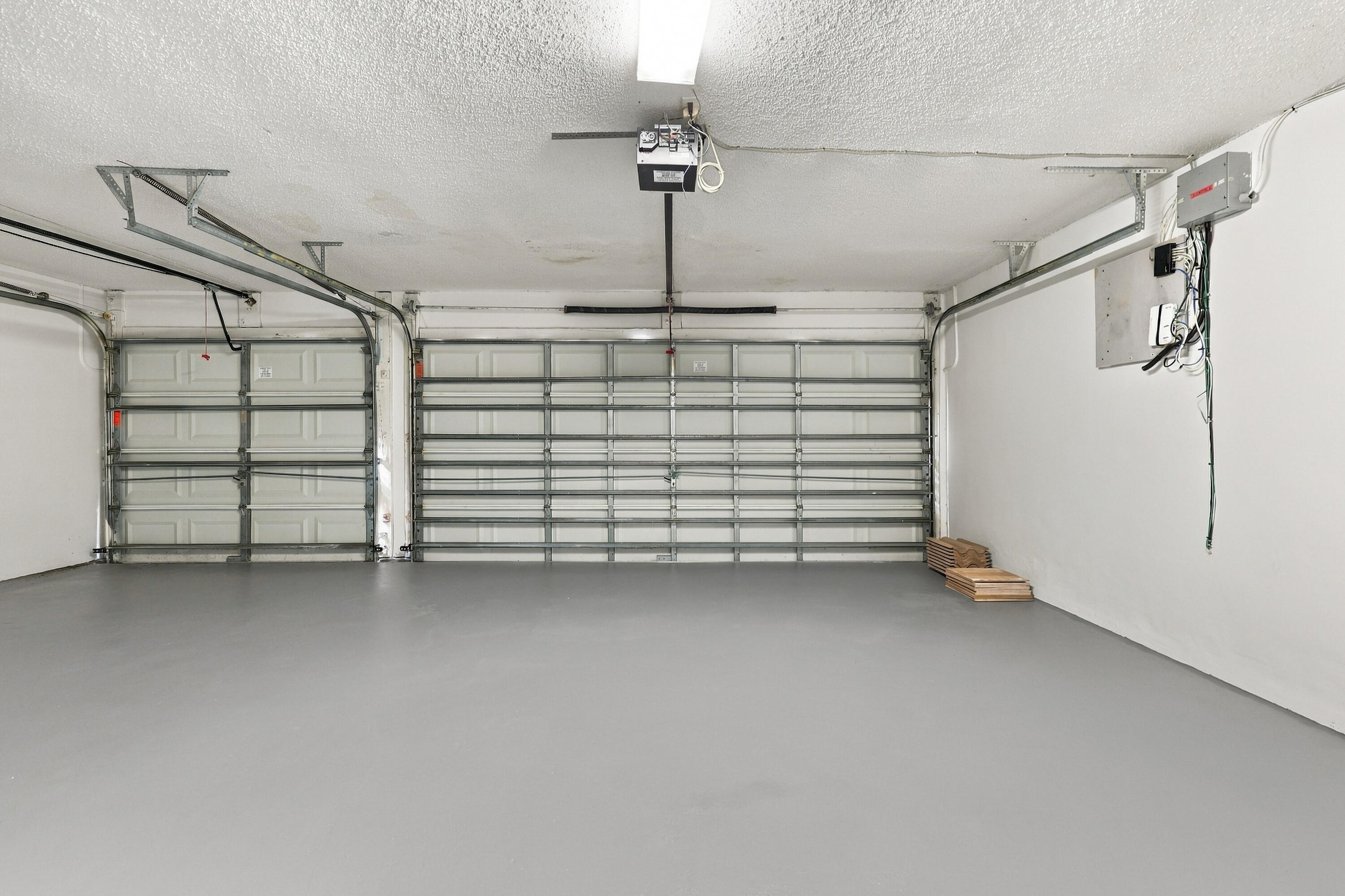 An impressive three-car garage featuring a finished floor, multiple overhead doors, and exceptional room for vehicles, recreational equipment, and additional storage.