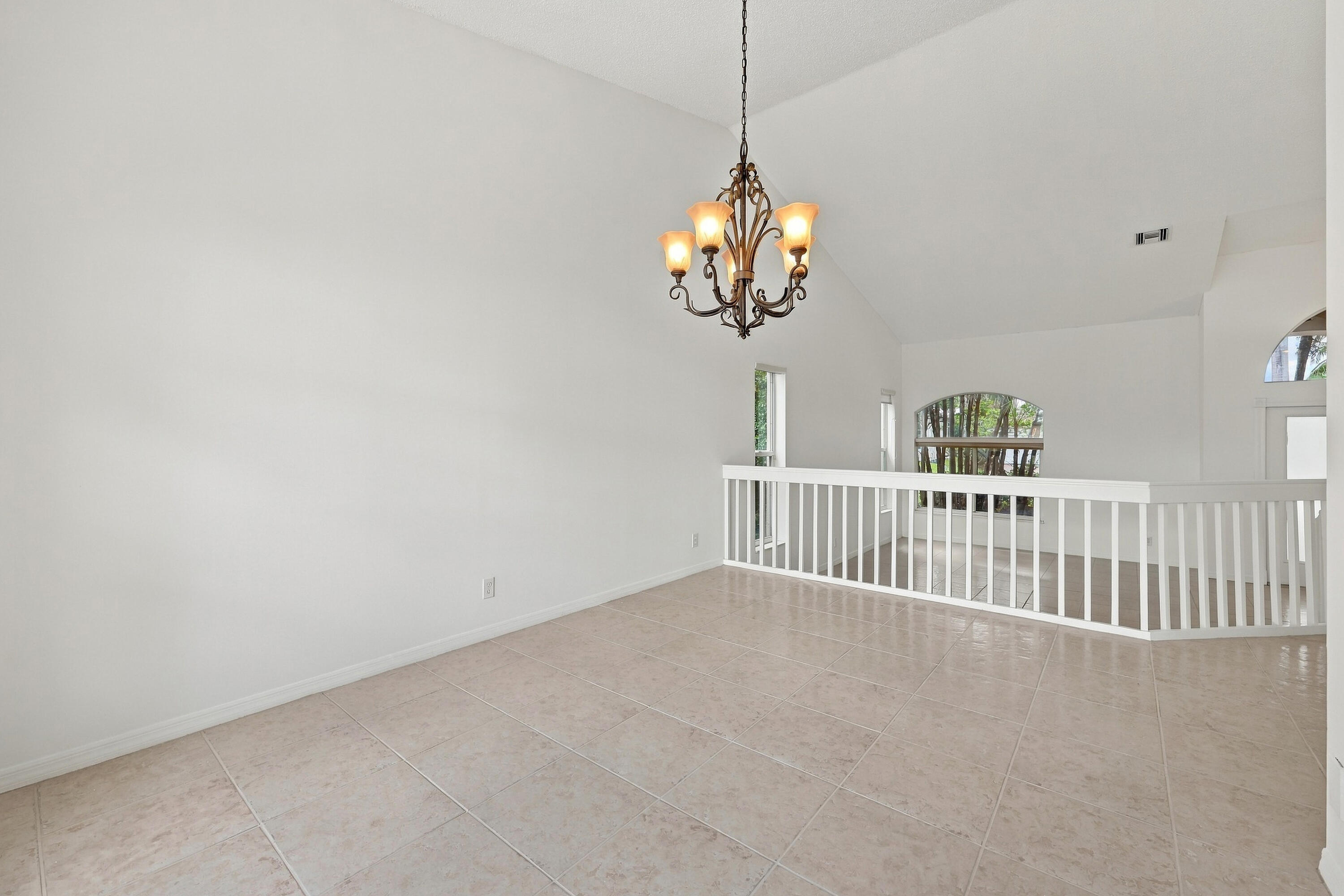 A decorative chandelier, dramatic arched window, and vaulted ceilings provide an elegant setting for both intimate dinners and larger celebrations. A decorative chandelier, dramatic arched window, and vaulted ceilings provide an elegant setting for both intimate dinners and larger celebrations.