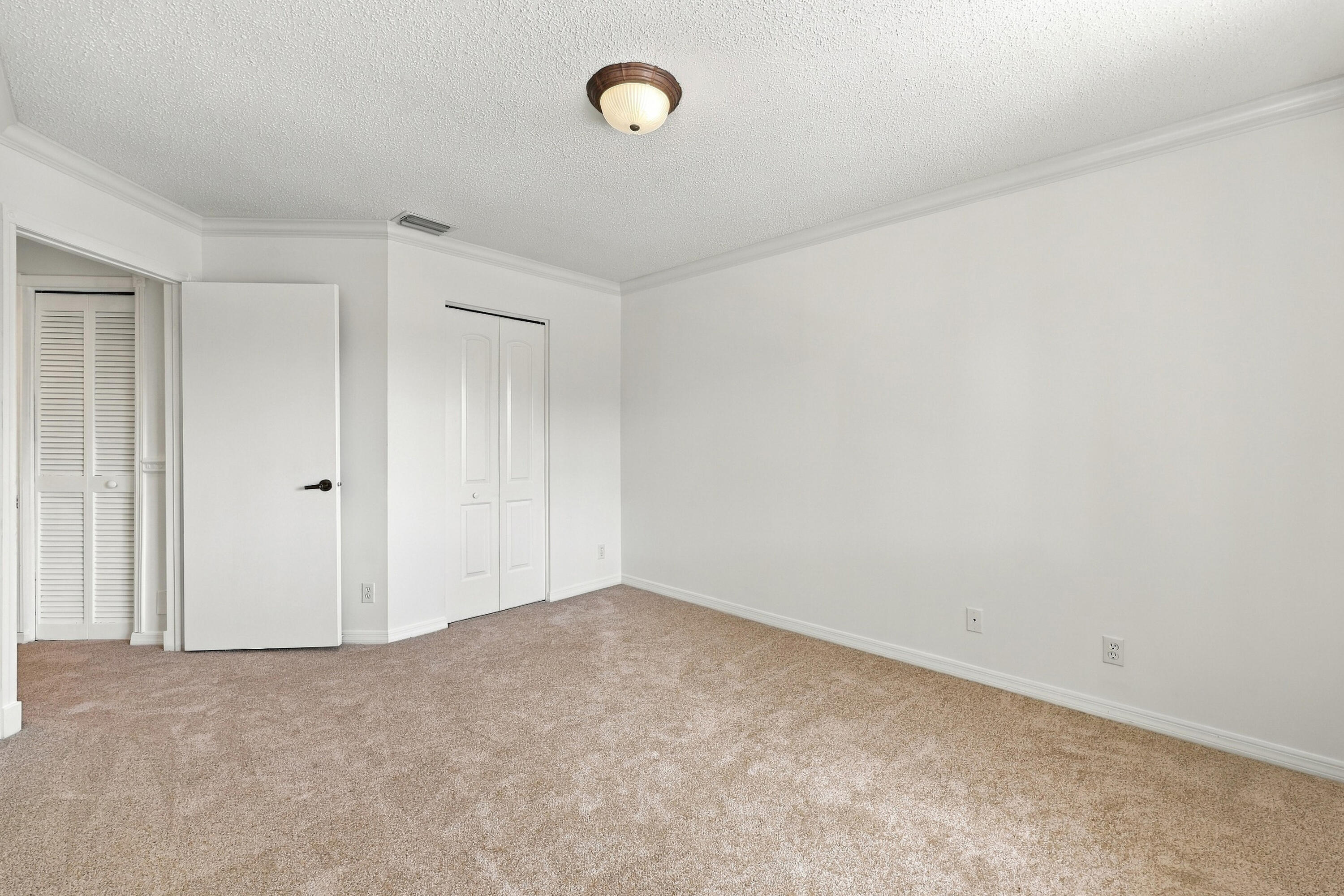 This inviting fourth bedroom features plush carpeting, neutral finishes, decorative crown molding, and a generous layout offering plenty of flexibility.