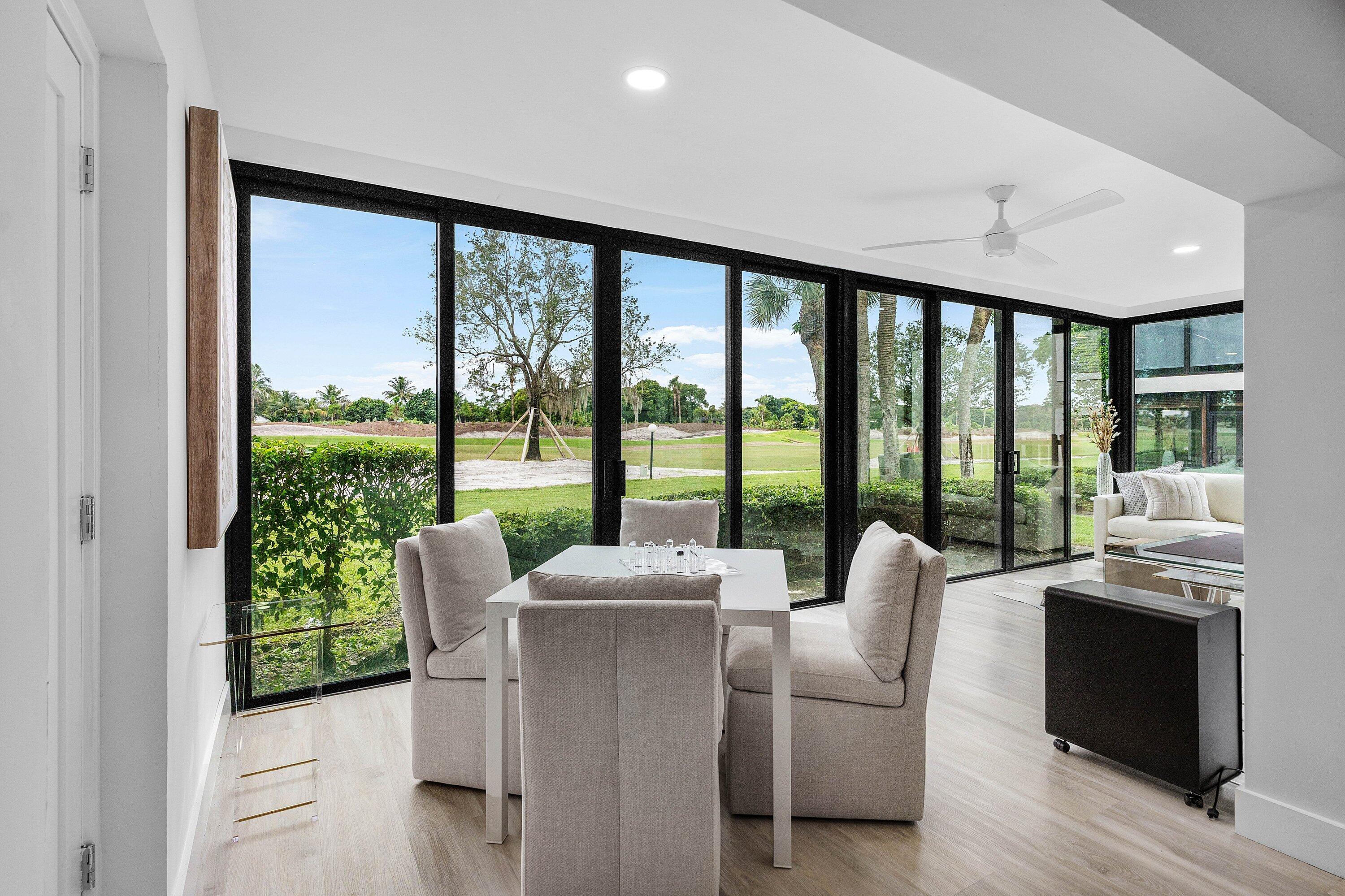 Floor-to-ceiling black-framed glass sliding doors, wood-finish flooring, recessed lighting, and a white ceiling fan