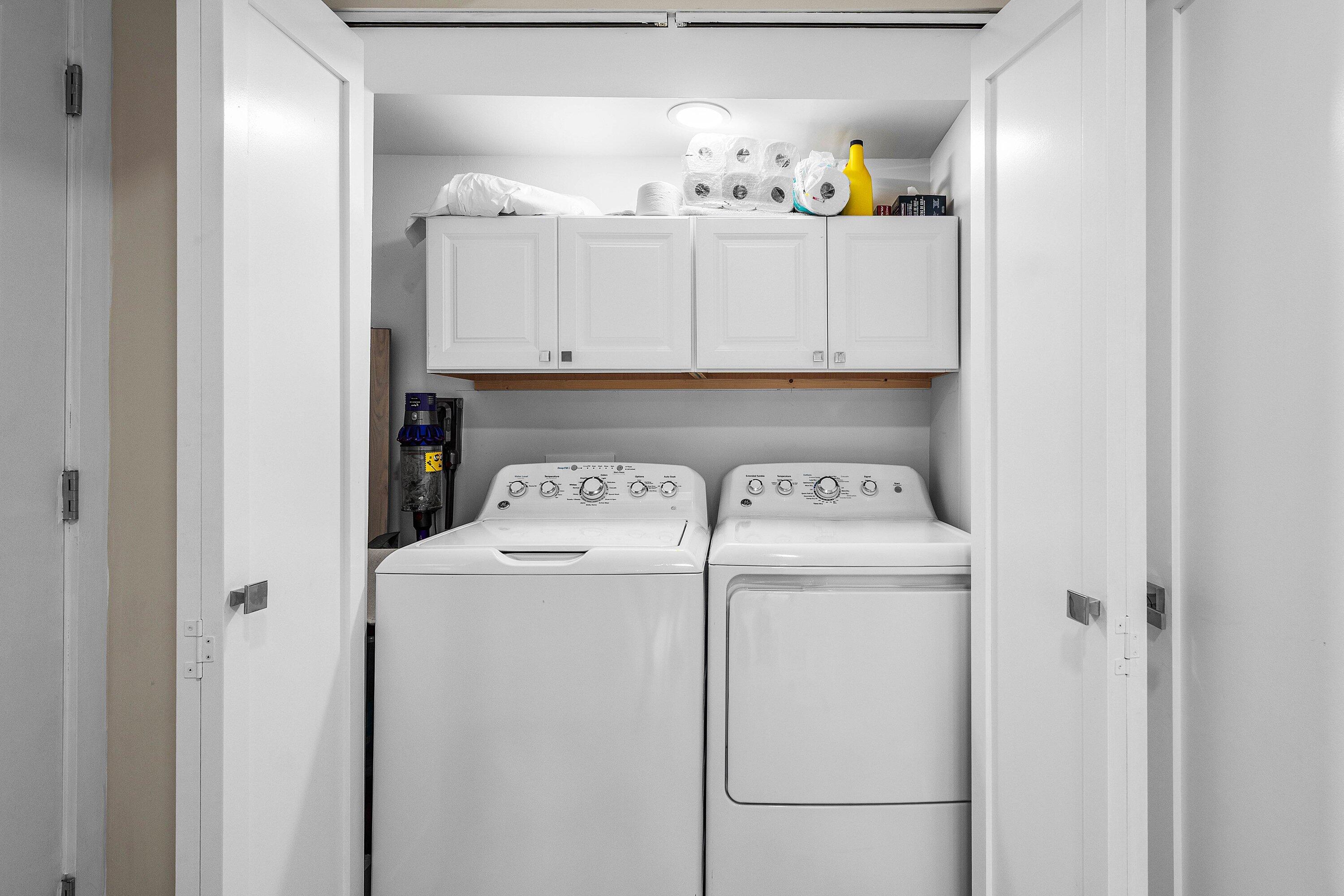 Dedicated laundry closet featuring white upper cabinetry, dual bi-fold doors, and recessed ceiling lighting