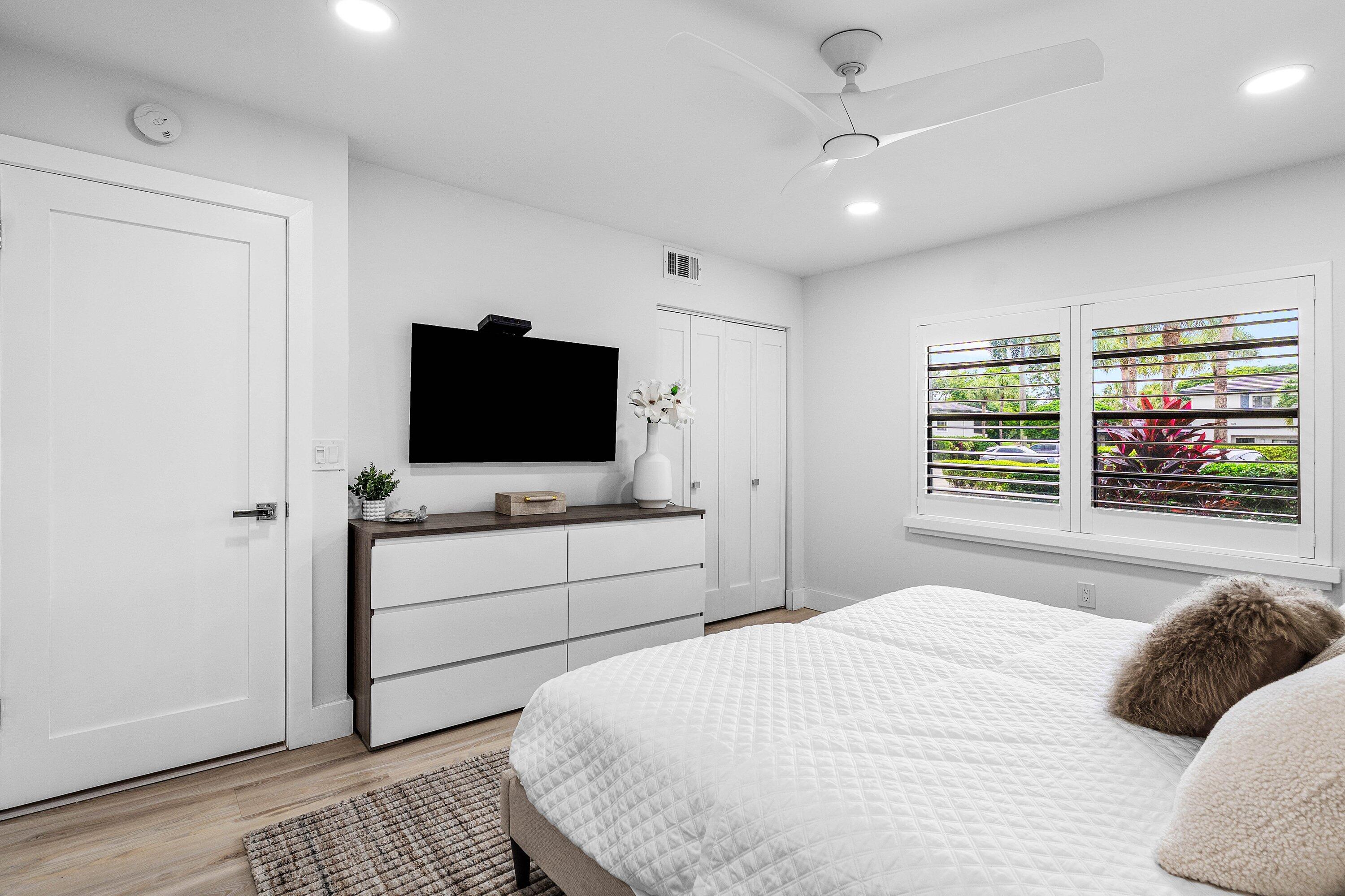 Room featuring wood-finish flooring, white plantation shutters, a modern white ceiling fan, and recessed lighting