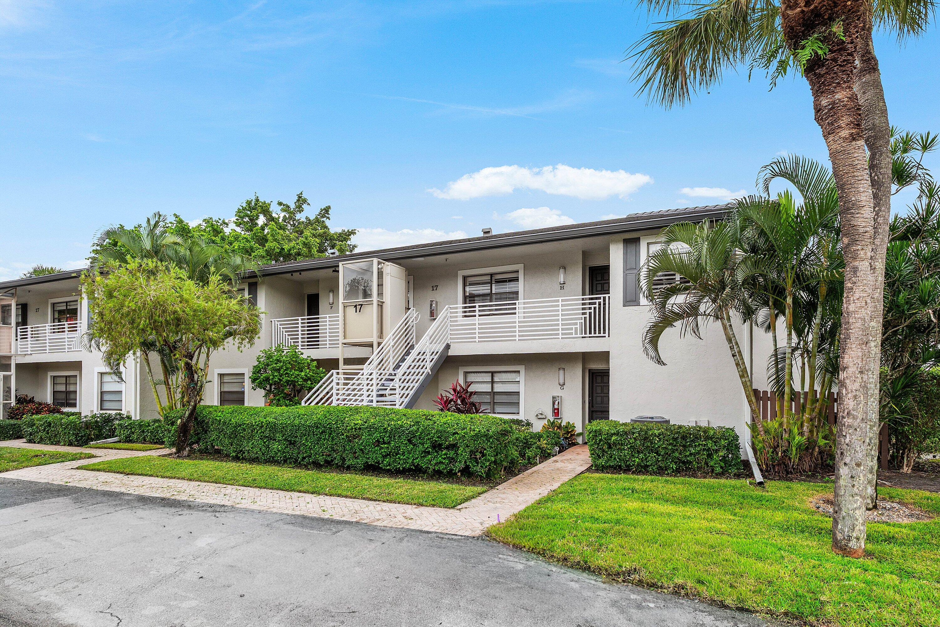 Multi-story exterior featuring a neutral stucco facade, metal railing balconies, a structural outdoor lift, and manicured landscaping