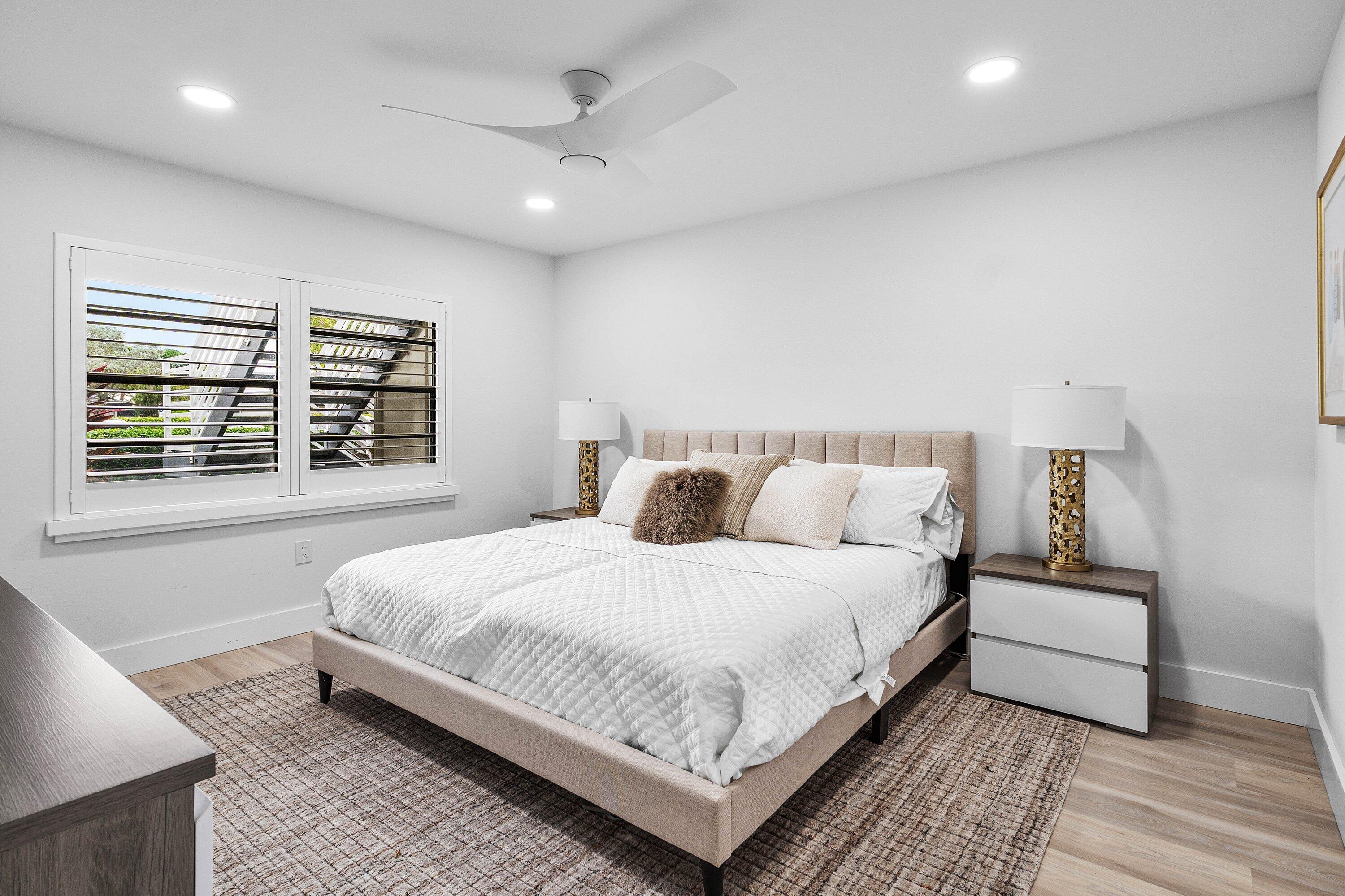 Neutral-toned interior featuring wood-finish flooring, recessed lighting, a modern three-blade ceiling fan, and window shutters