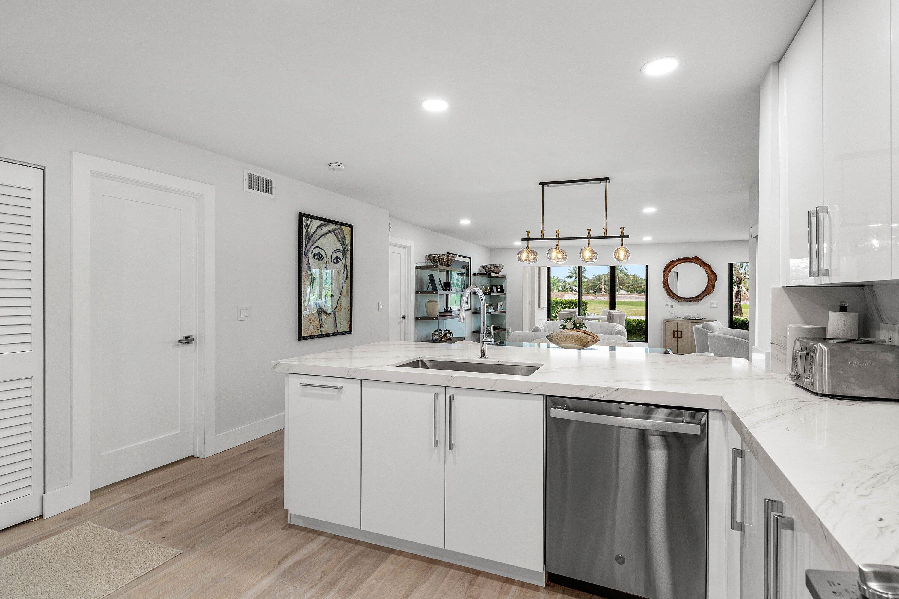 Kitchen featuring white cabinetry, stone-finish countertops, stainless steel dishwasher, integrated sink faucet, and wood-finish flooring