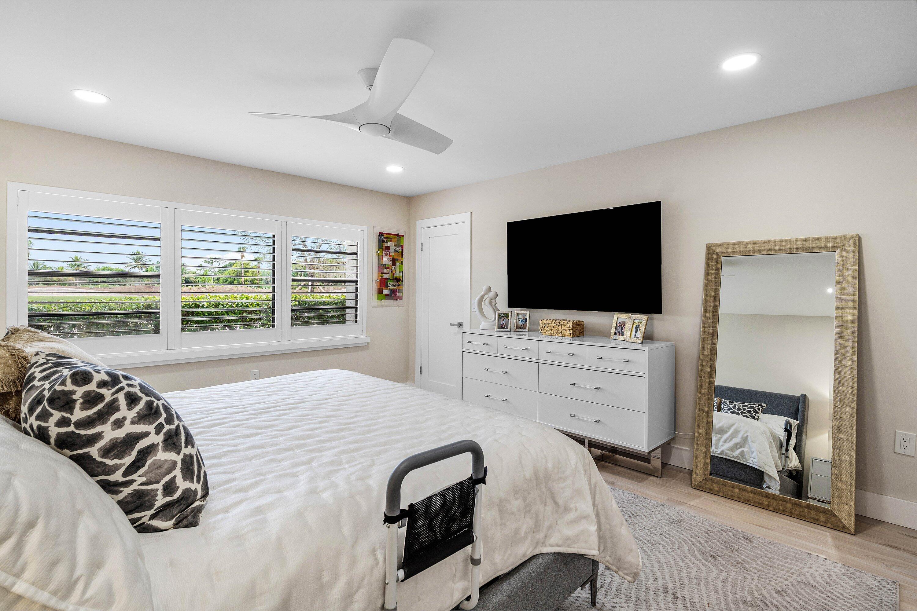 Recessed lighting, three-pane horizontal window configuration with integrated shutters, and a three-blade ceiling fan