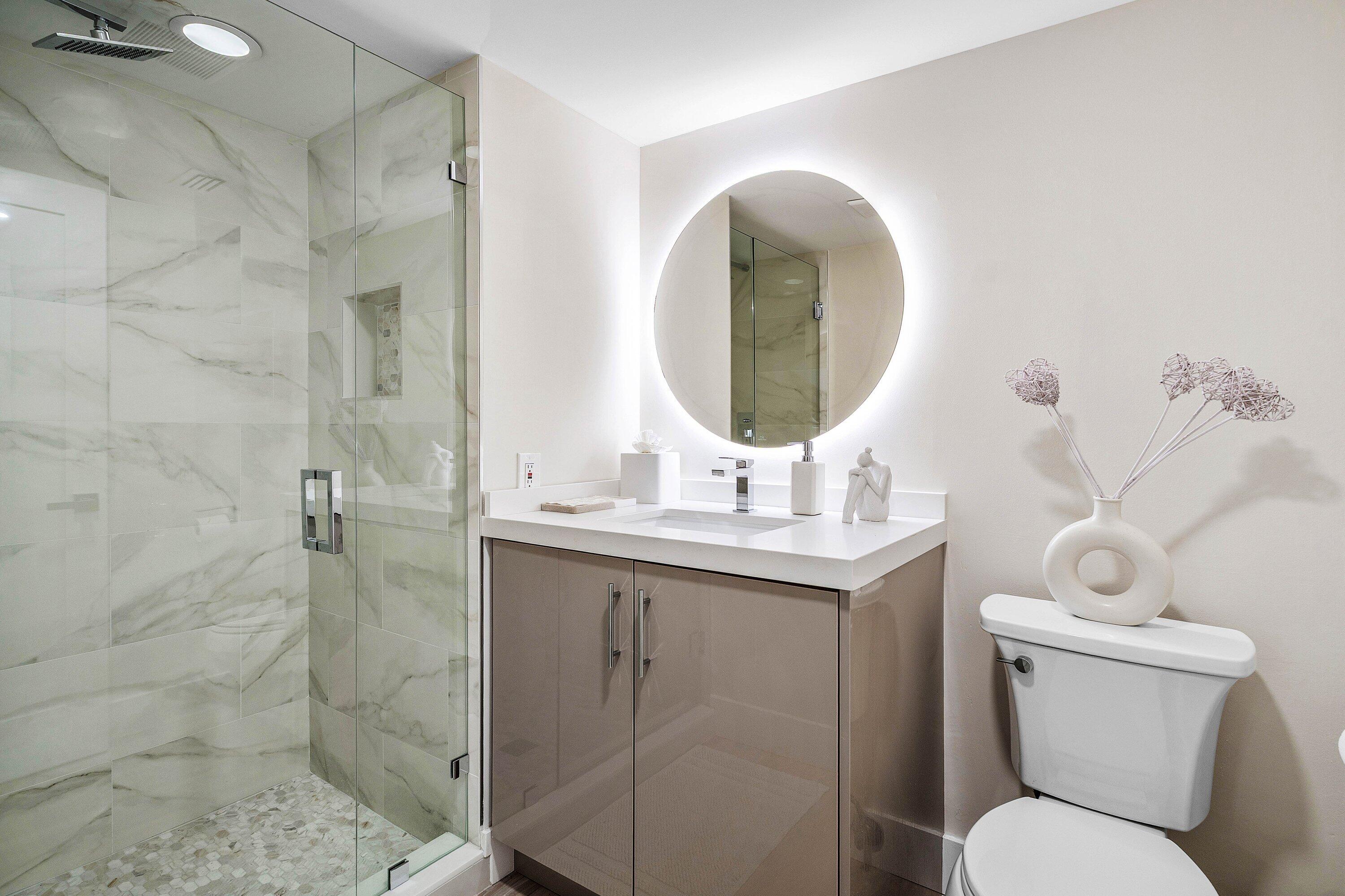 Bathroom featuring a glass-enclosed shower with stone-tile surround, pebble flooring, and integrated shower niche
