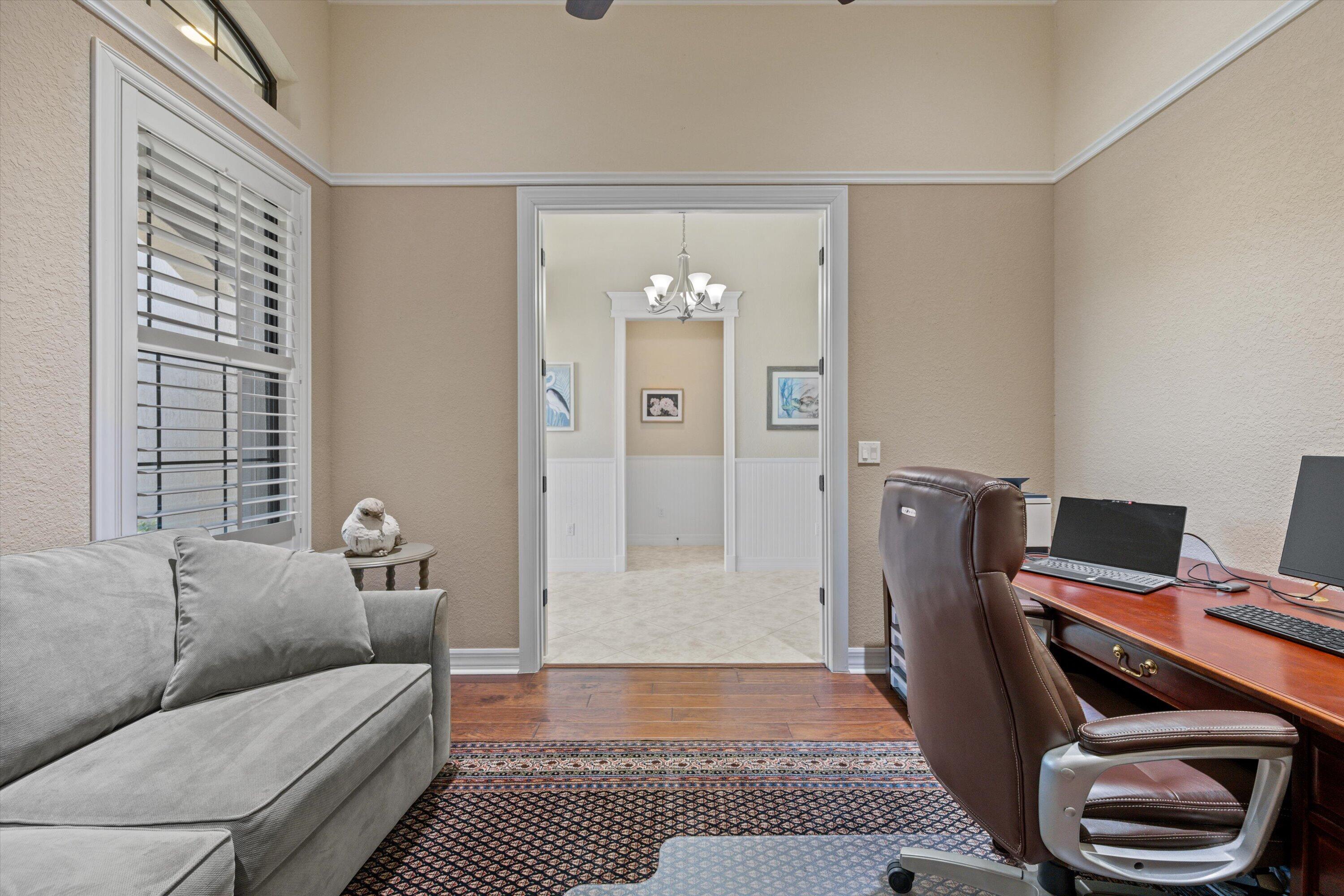 Room featuring high ceilings, wood-finish flooring, crown molding, and a wide doorway with decorative trim