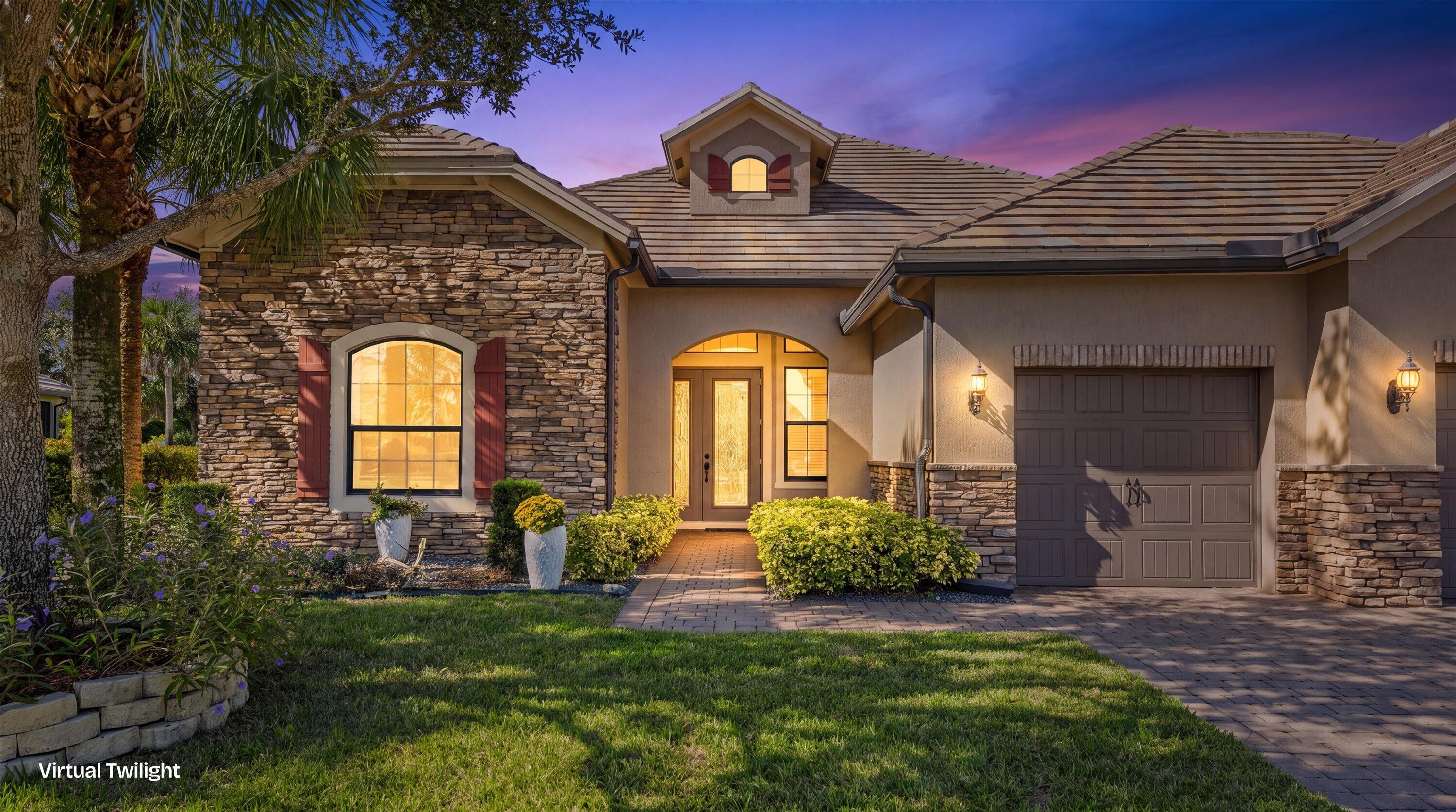 Exterior featuring stone siding, tile roof, arched entryway with double doors, and paved driveway