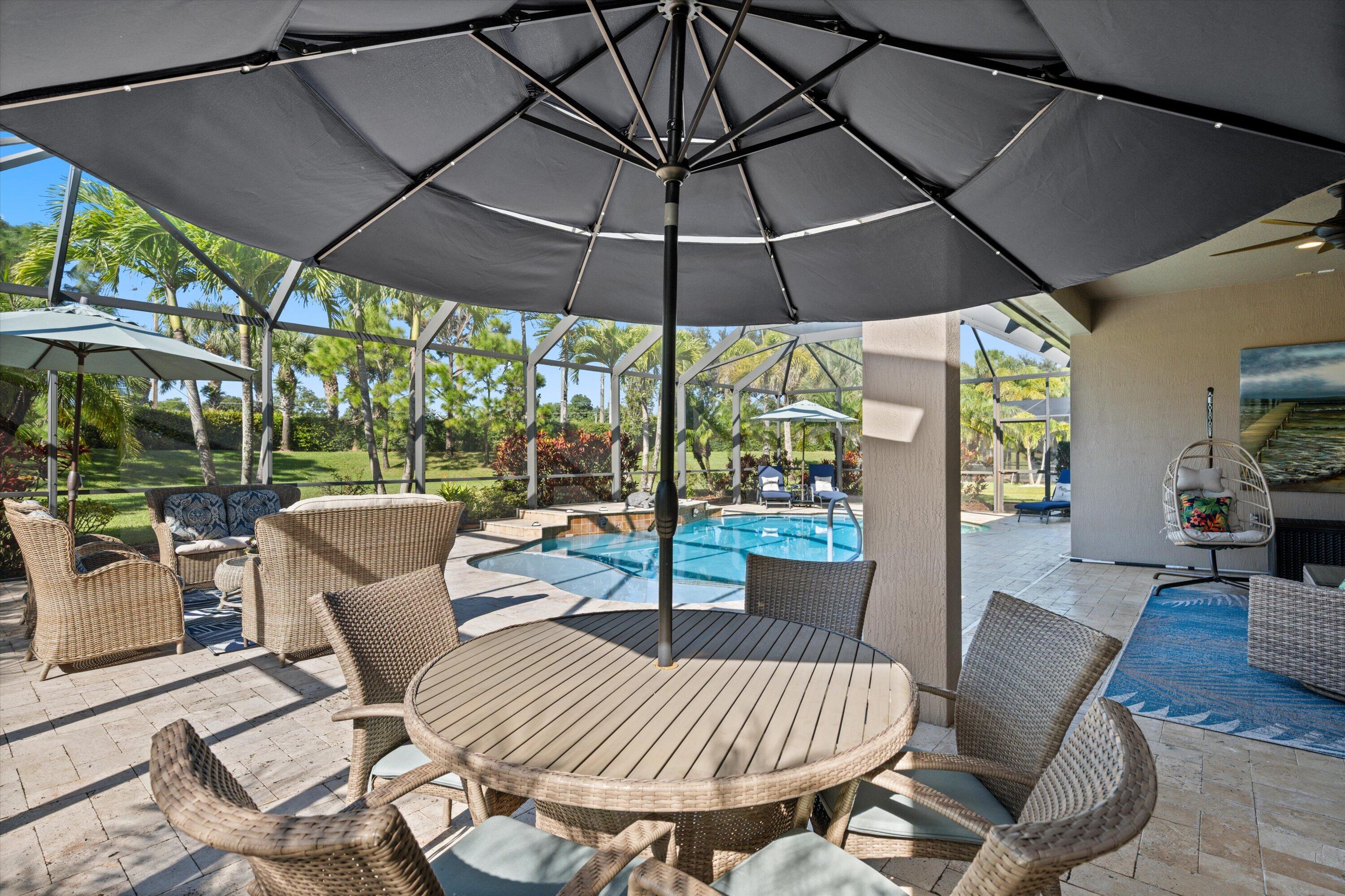 Screened lanai featuring paver flooring, custom pool with built-in spillway, and ceiling fan