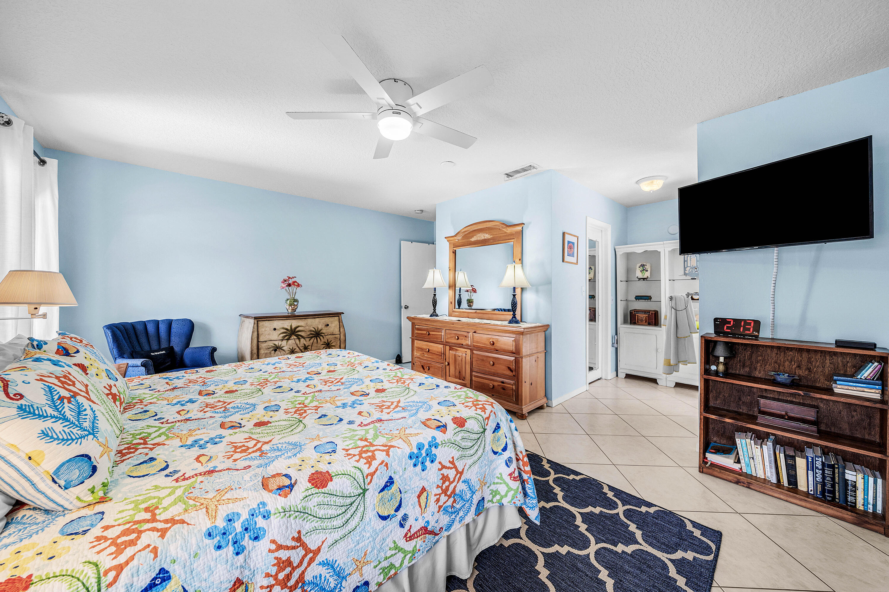 Spacious room featuring tile flooring, a central ceiling fan with integrated lighting, and built-in white cabinetry
