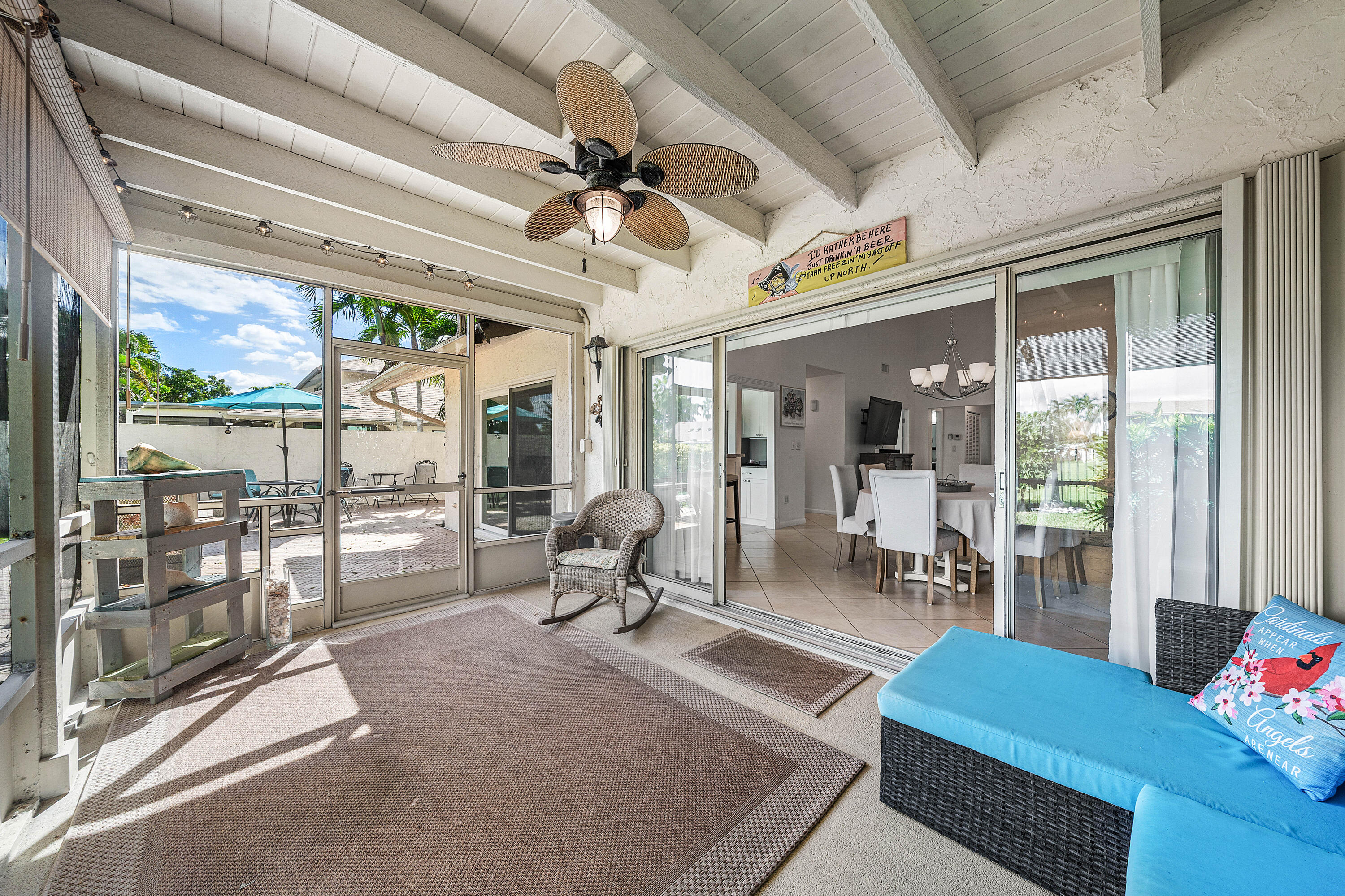 Screened-in patio featuring an exposed beam ceiling, ceiling fan with integrated lighting, and glass sliding doors