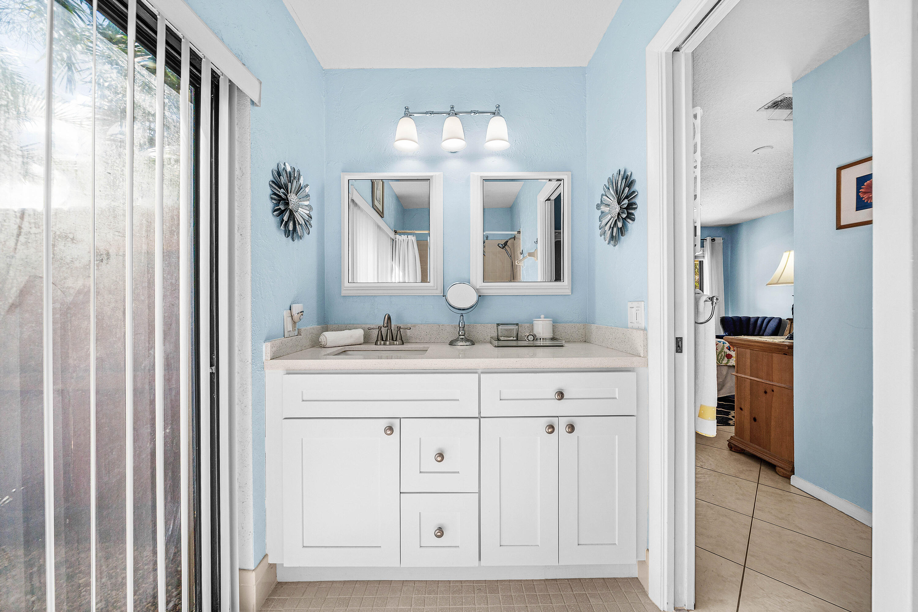 Bathroom vanity featuring white cabinetry, a neutral stone-look countertop, dual square-framed mirrors, and a three-light fixture