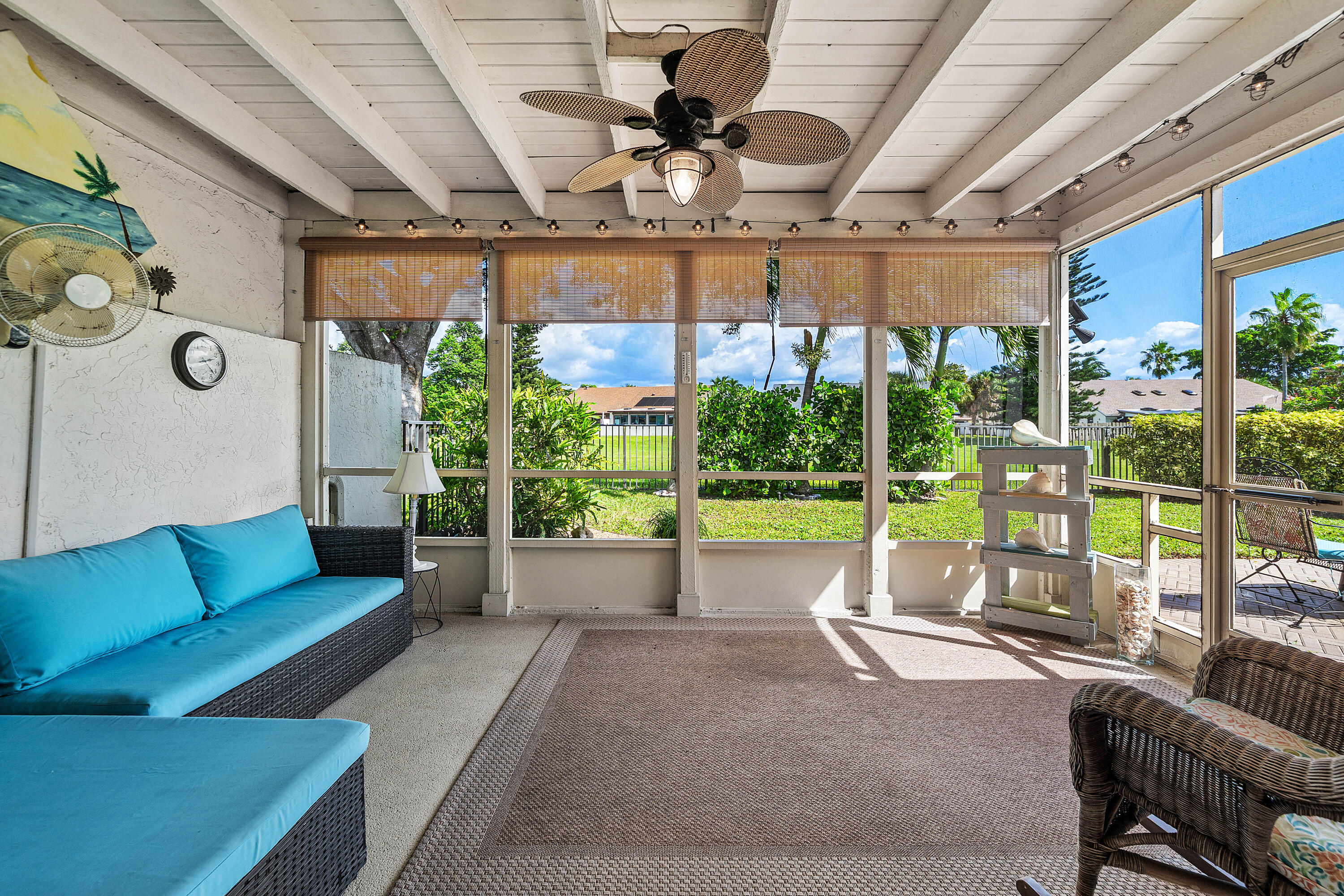 Enclosed patio featuring a painted exposed-beam ceiling, ceiling fan with integrated lighting, concrete flooring, and screen-wall construction