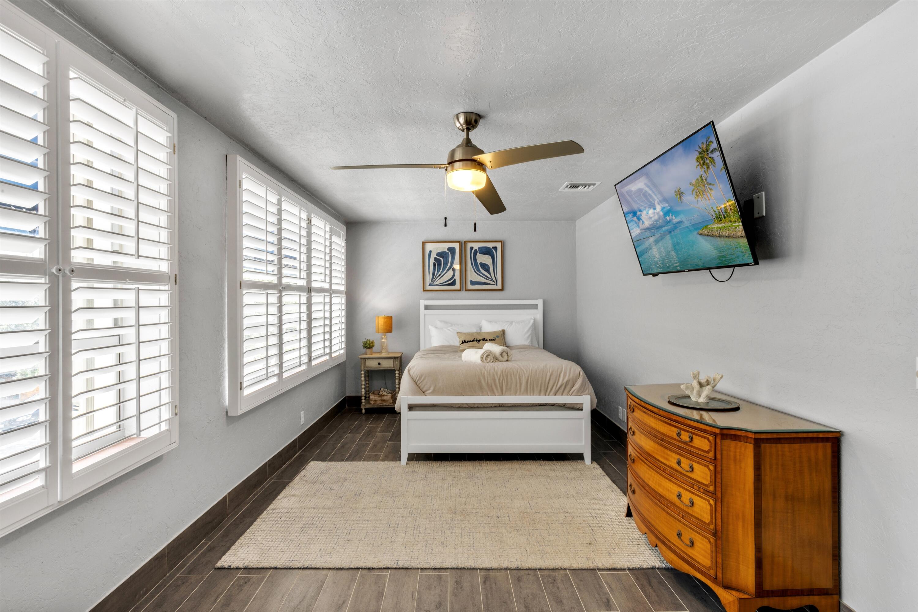 Wood-finish flooring, plantation shutters, and a central ceiling fan with integrated lighting