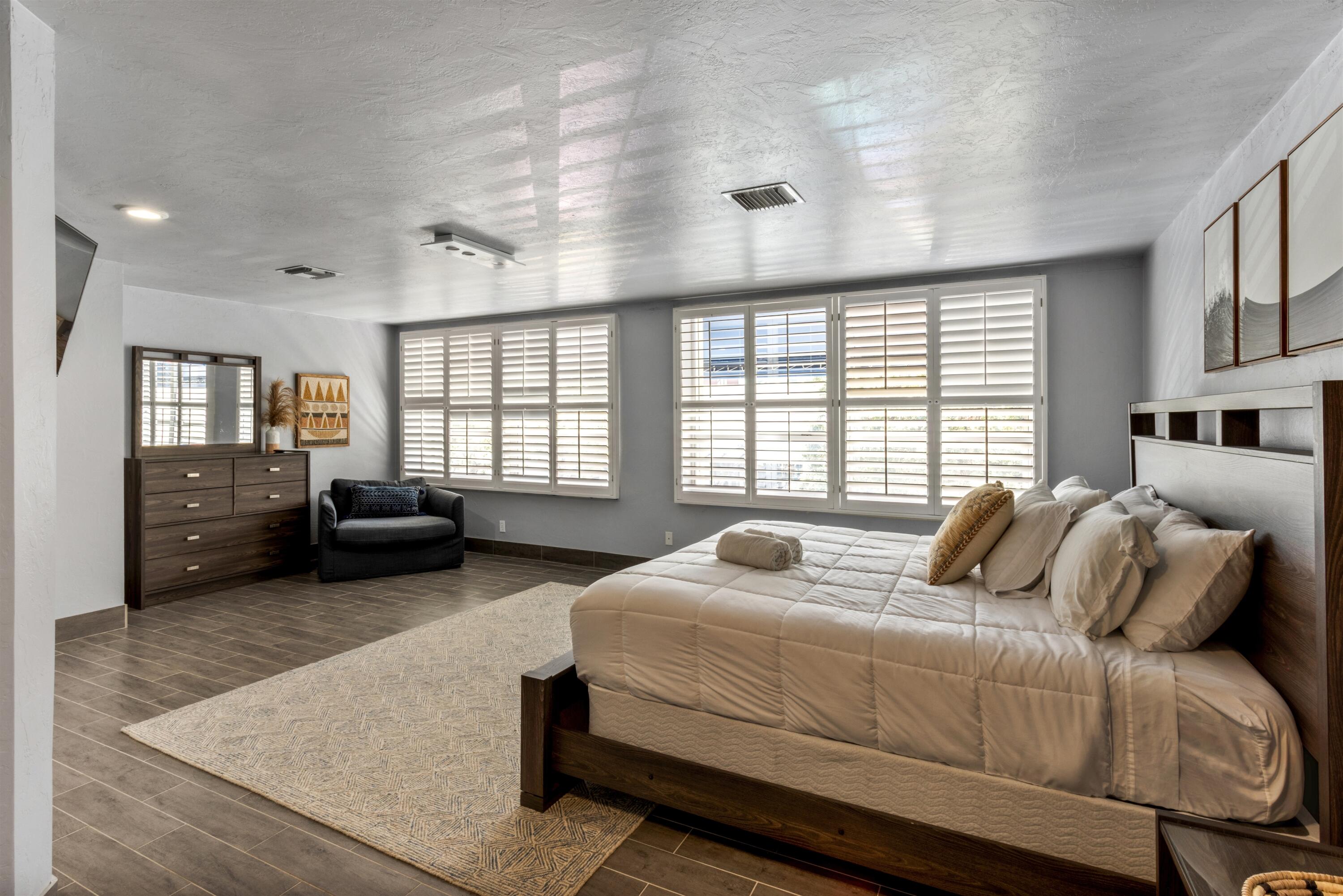 Spacious room featuring wood-finish flooring, dual windows with plantation shutters, recessed ceiling lighting, and smooth-finish ceilings