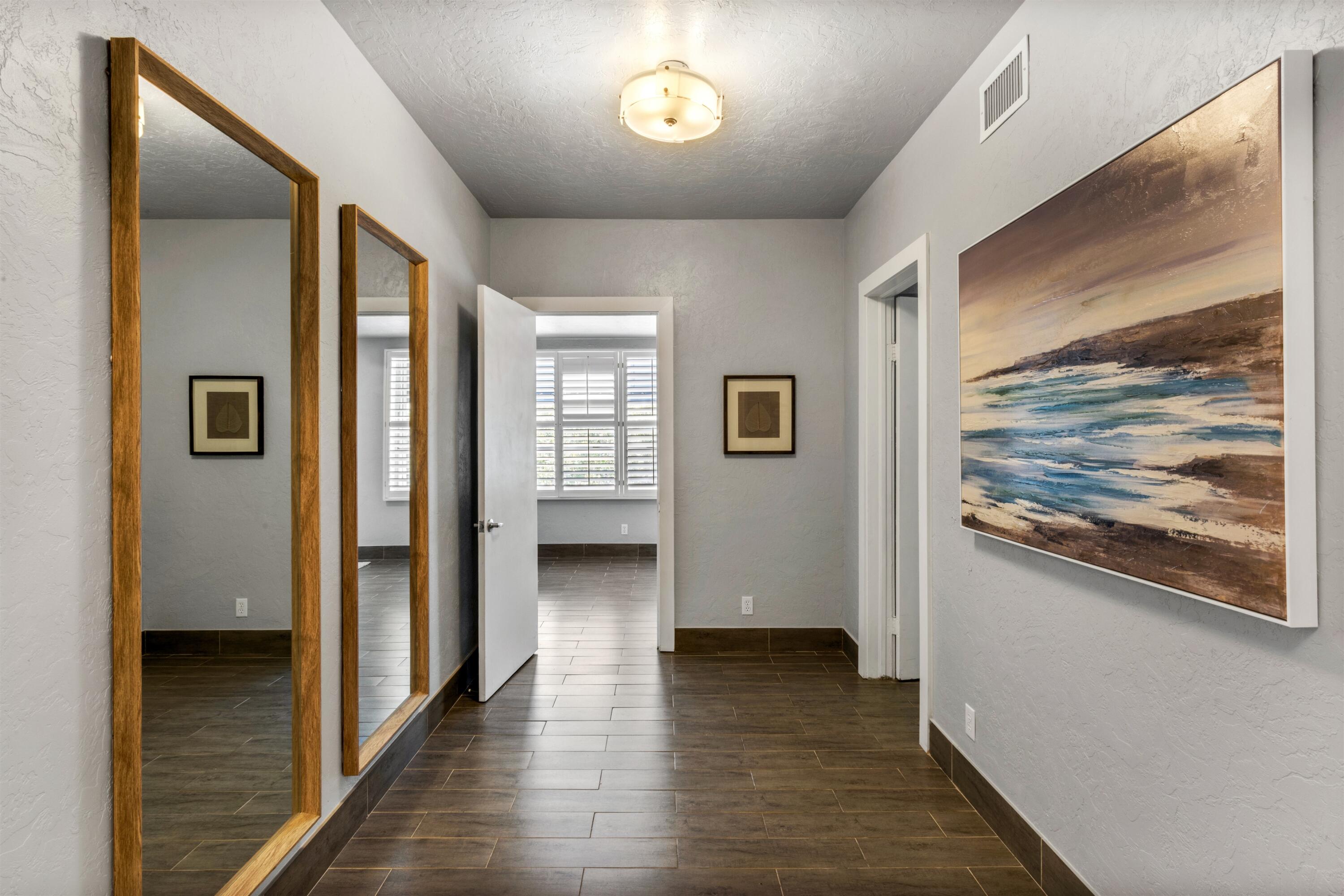 Hallway featuring tile flooring, two full-length wall-mounted mirrors with wood-finish frames, and a flush-mount dome light fixture