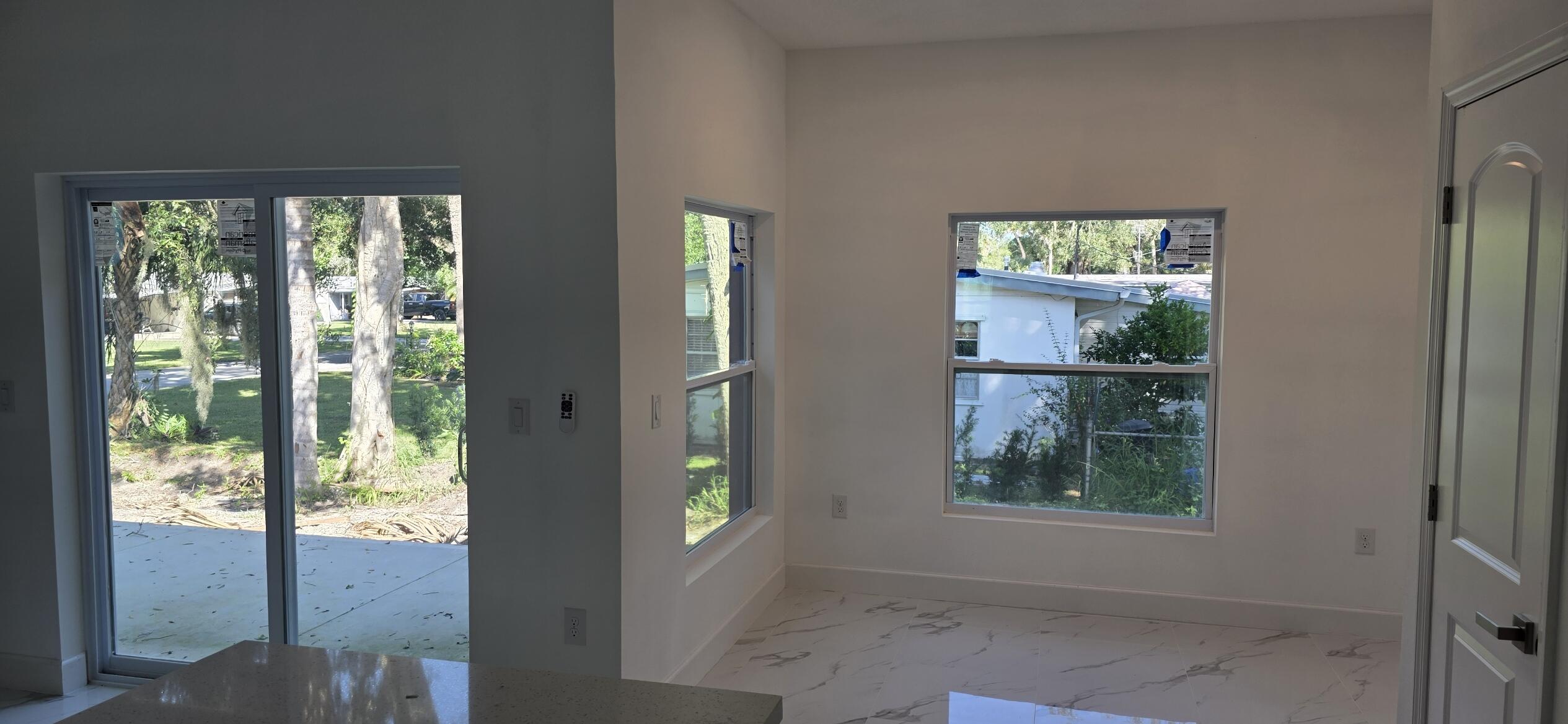 Interior area featuring large-format tile flooring, double-pane windows, sliding glass door, and solid-core panel door