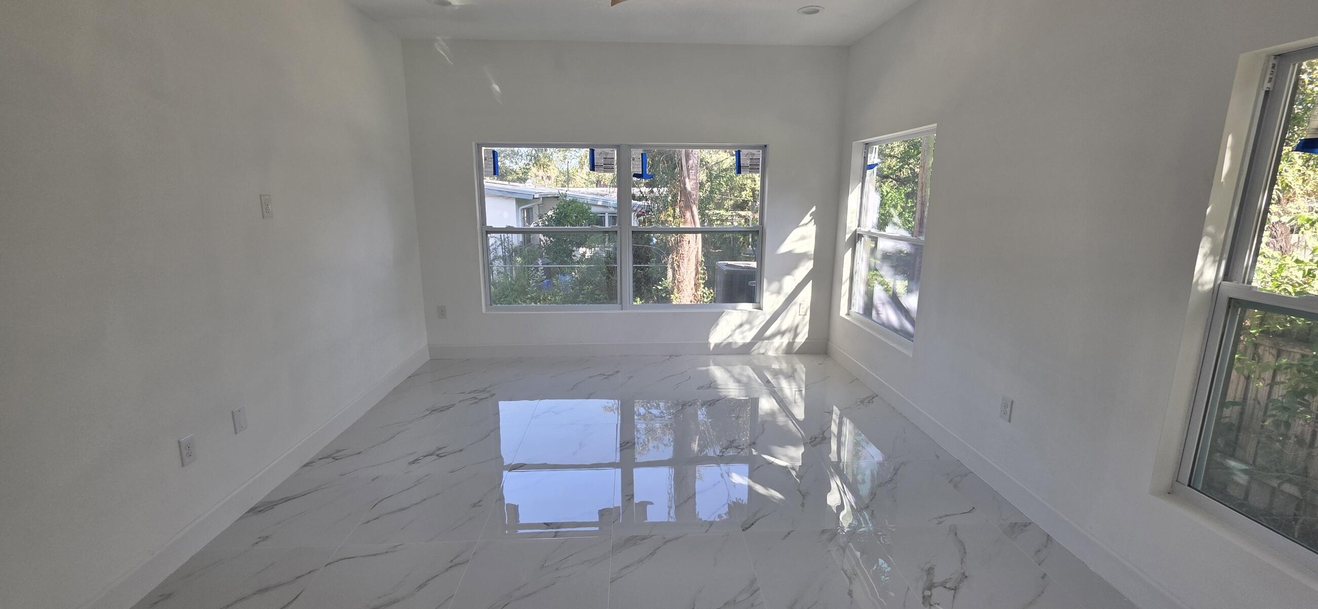 Polished white tile flooring with gray veining, multiple multi-pane windows, and recessed ceiling lighting