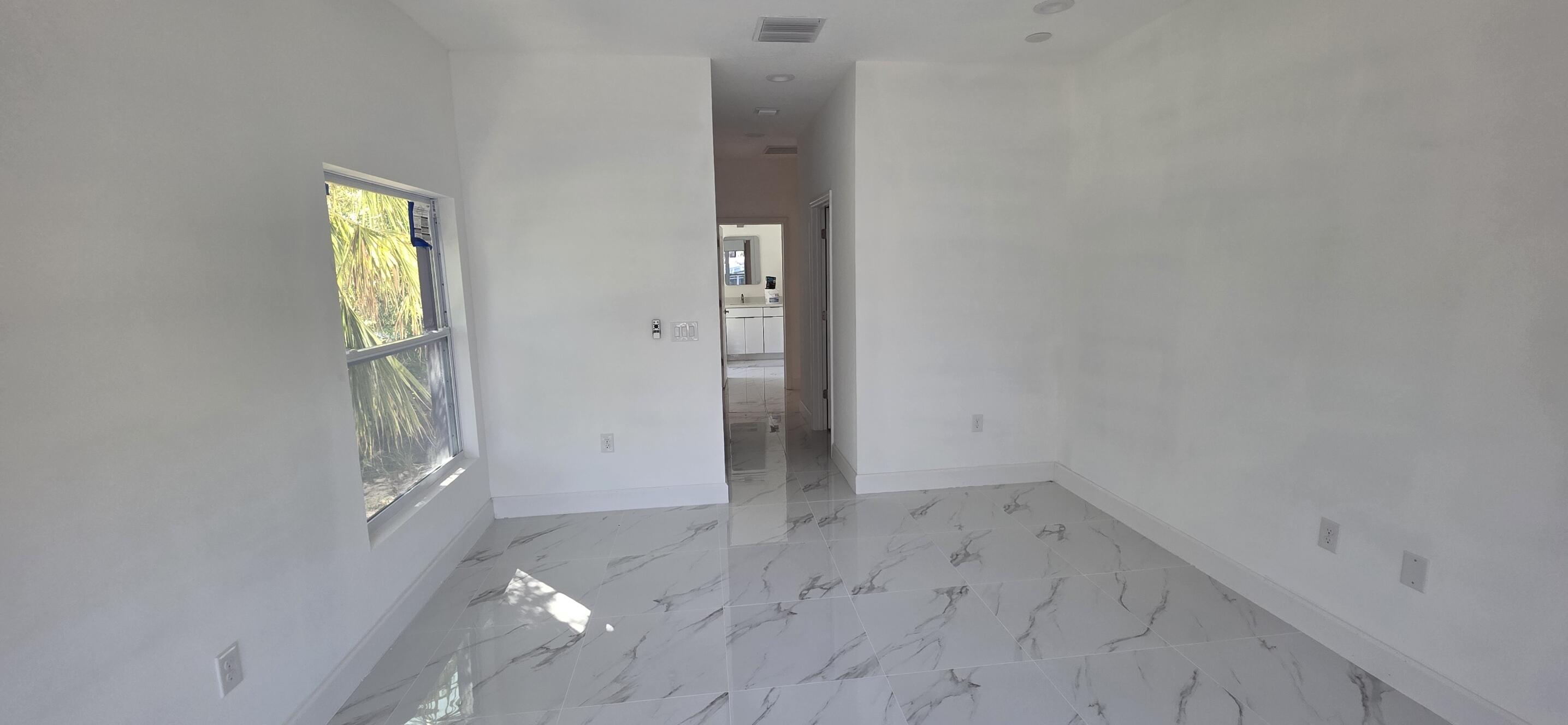 Large-format tile flooring with veined detailing, recessed ceiling lighting, and a single-pane window