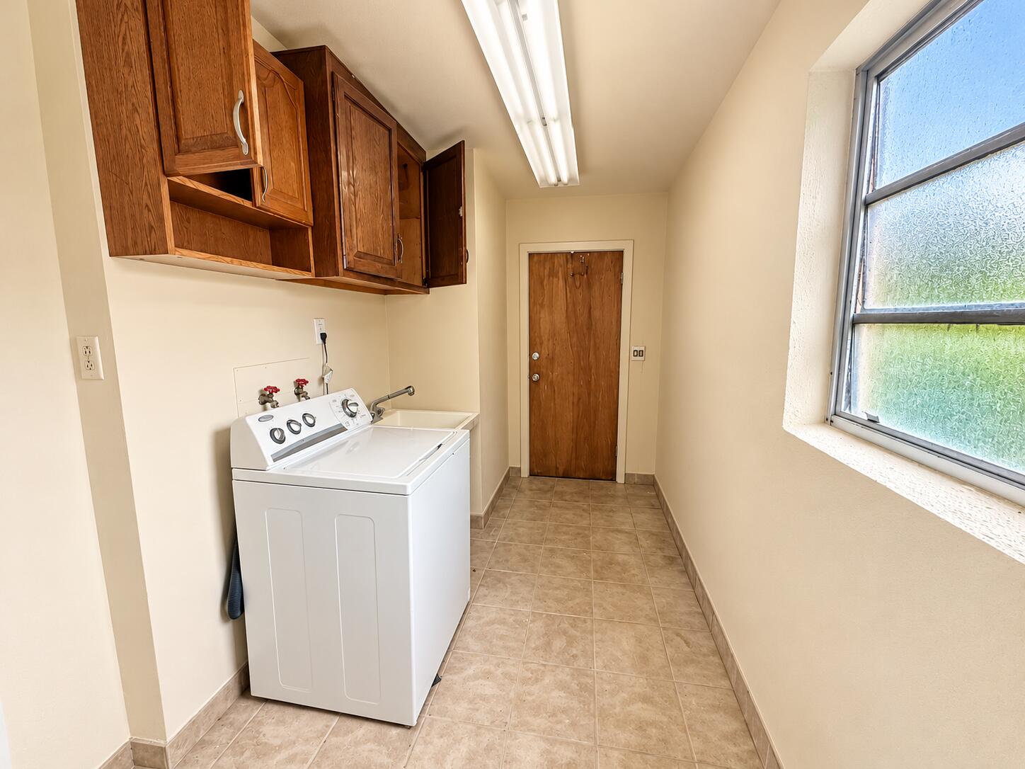 Bright Narrow Laundry Room with Wood Cab