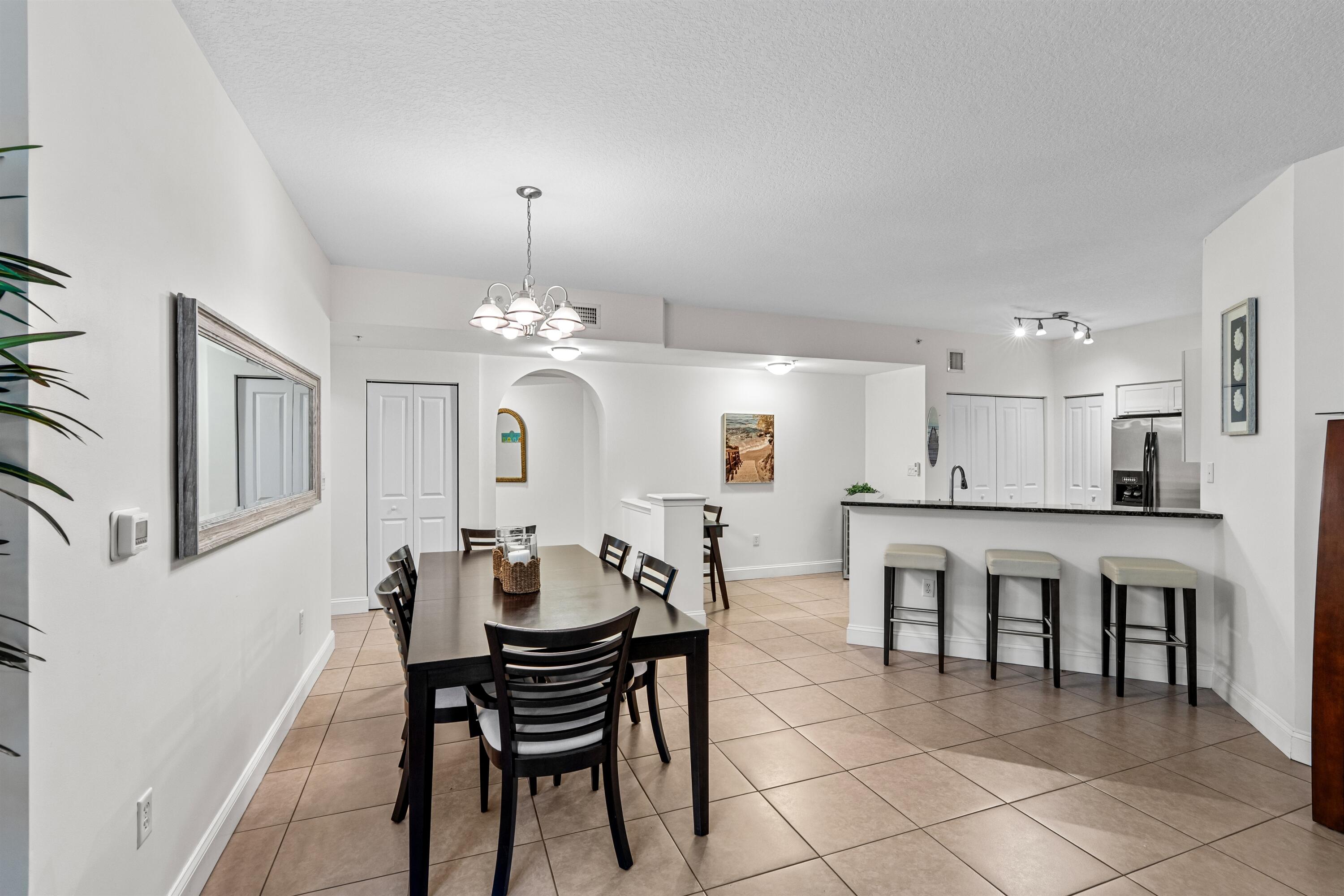 Open-concept interior featuring tile flooring, a kitchen breakfast bar with dark stone-finish countertops, a multi-light chandelier, and recessed ceiling lighting