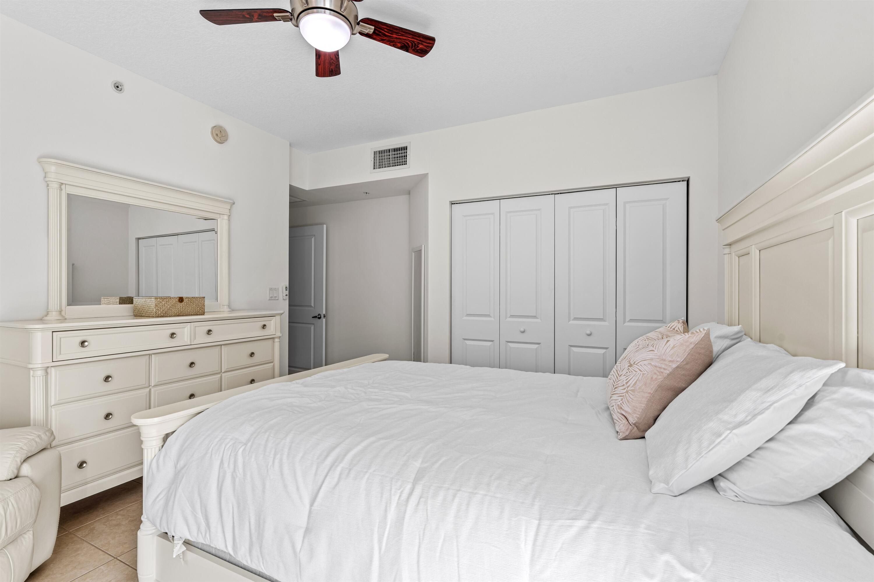Room featuring neutral paint, tile flooring, built-in bi-fold closet doors, and a ceiling fan with integrated lighting