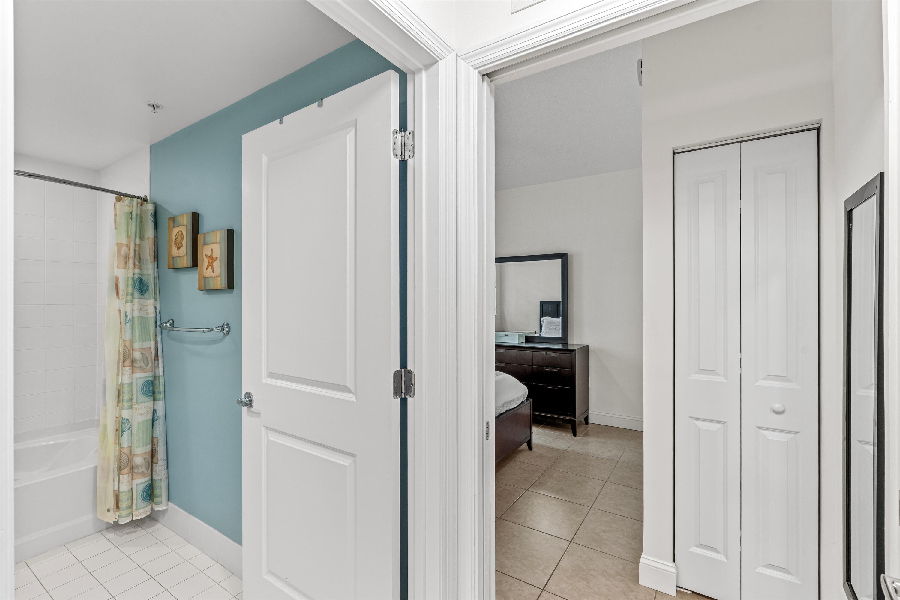 Bathroom featuring a tile-surround bathtub and a bifold closet door, complete with neutral tile flooring