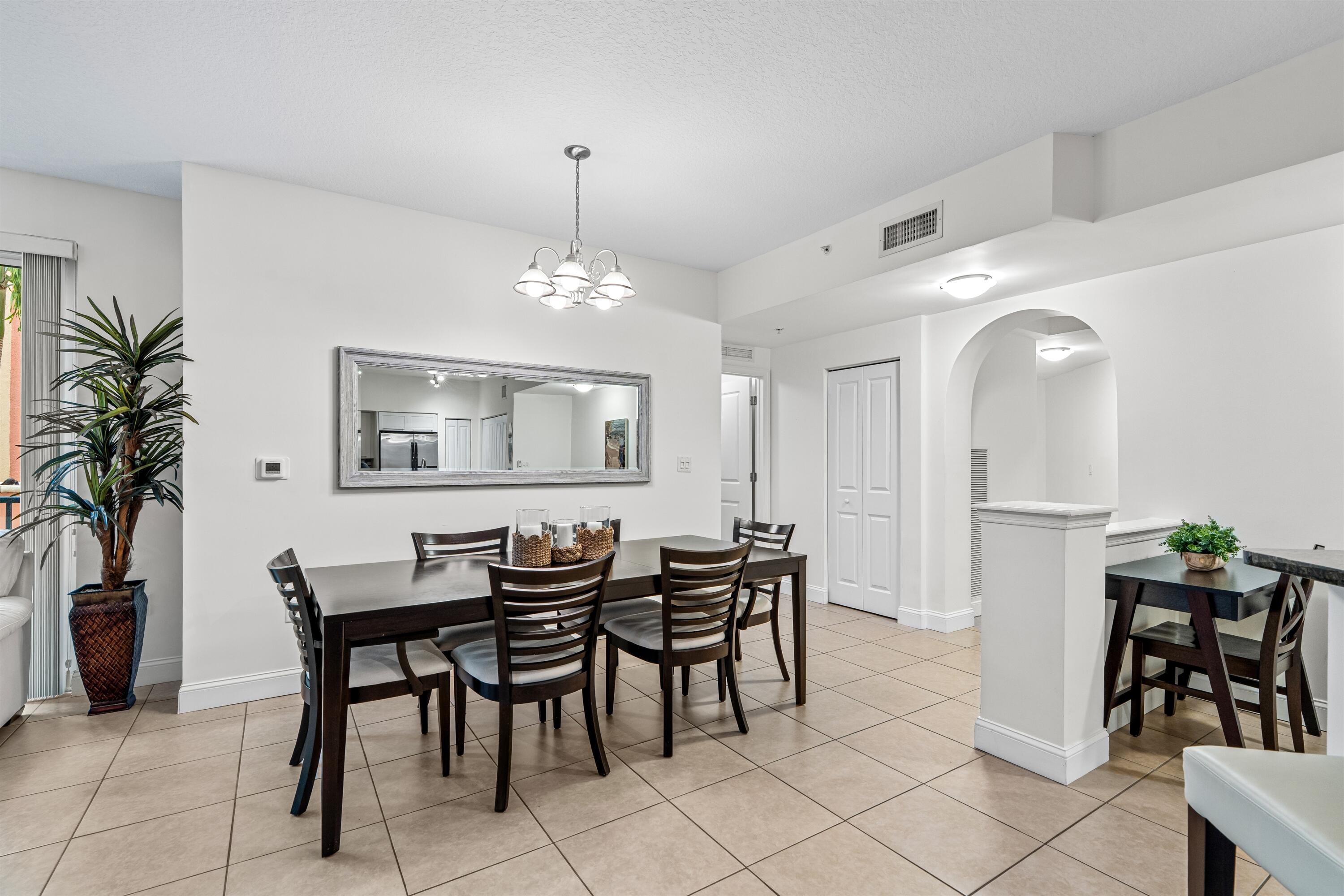 Open-concept space featuring tile flooring, a multi-light chandelier, a wall-mounted rectangular mirror, and an arched architectural opening