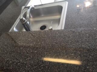 Stainless steel sink with a high-arc faucet set into a dark speckled countertop Stainless steel sink with a high-arc faucet set into a dark speckled countertop