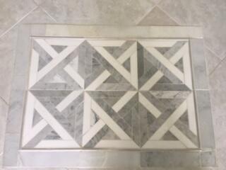 Decorative floor tile inlay featuring a geometric pattern and light-toned grout Decorative floor tile inlay featuring a geometric pattern and light-toned grout