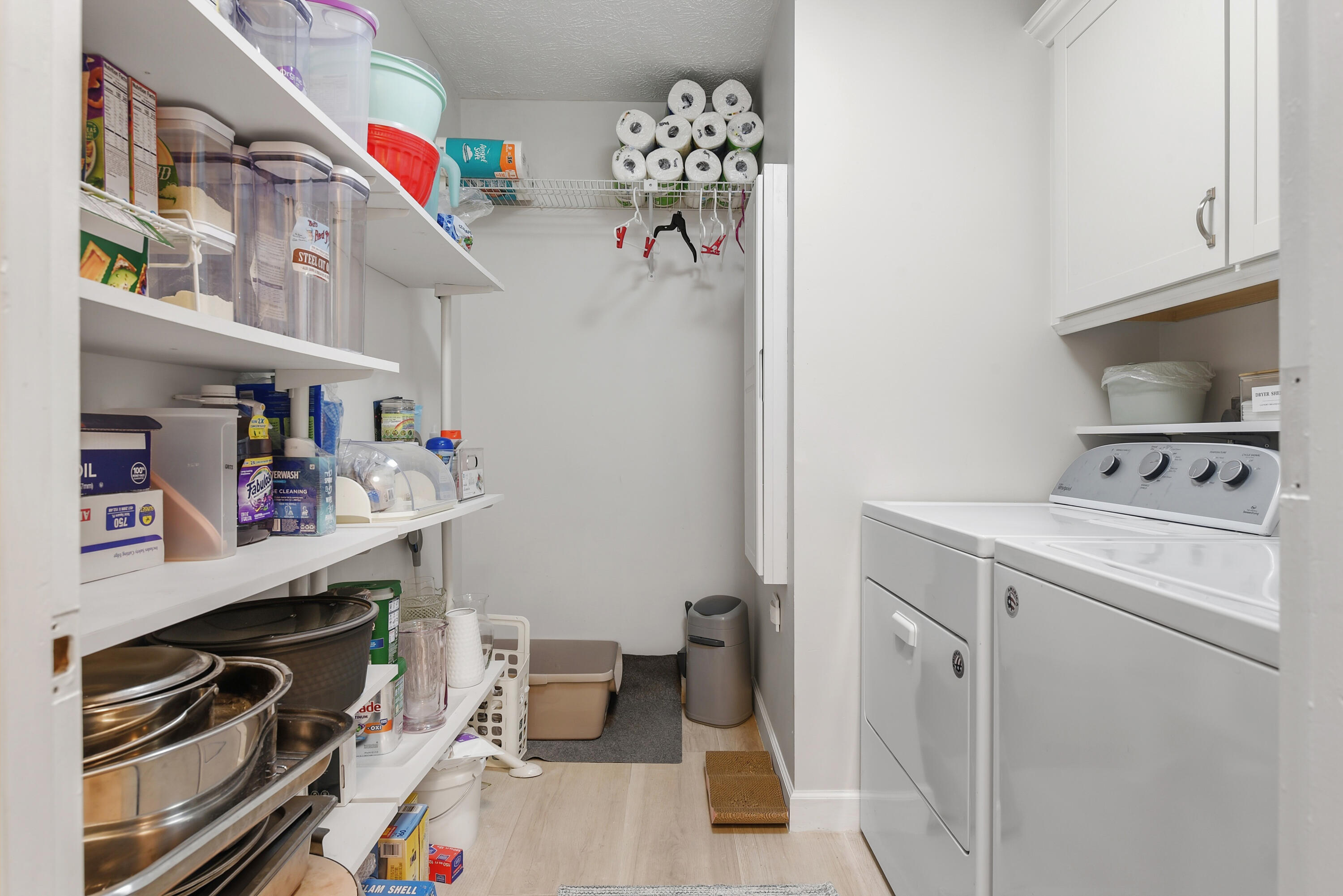 Convenient indoor laundry room featuring a washer and dryer, extensive built-in shelving, and additional cabinetry for organized storage.