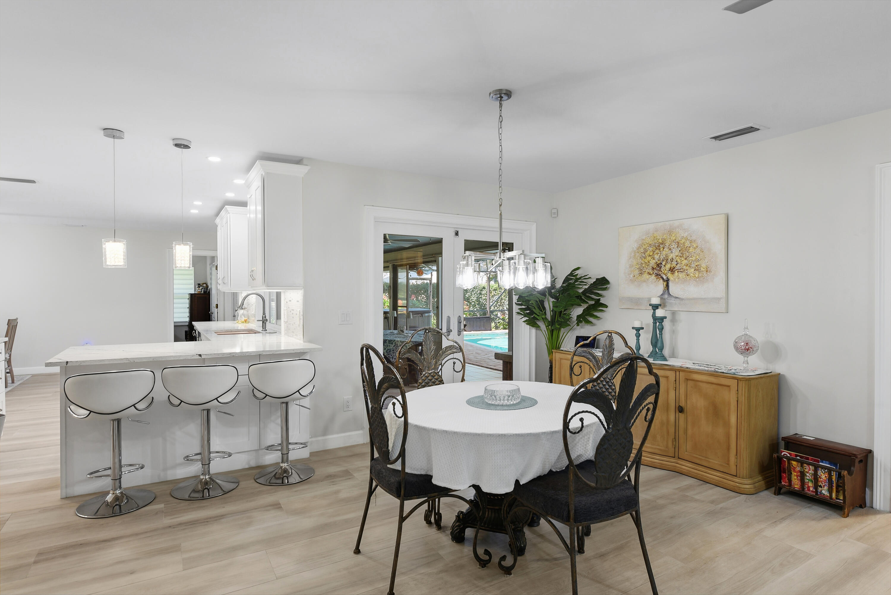Bright and inviting breakfast area overlooking the screened pool and lanai! Conveniently located beside the beautifully remodeled kitchen with breakfast bar seating, creating the perfect setting for casual dining and entertaining.