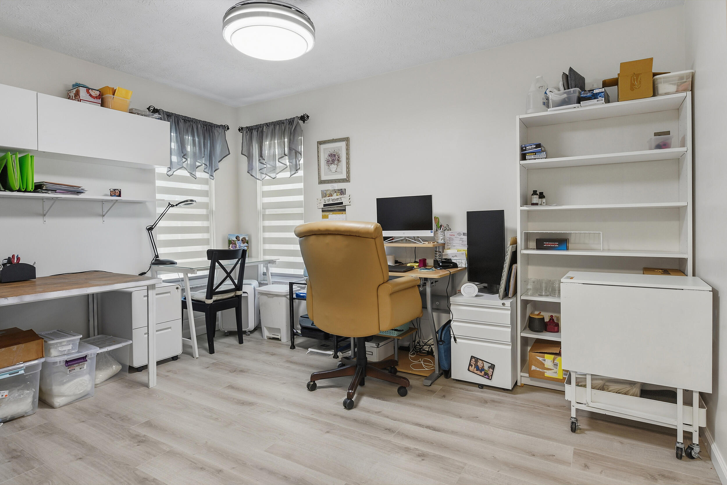 Flexible living space currently used as a home office, featuring attractive flooring, built-in storage, and natural light. Easily suited for a bedroom, hobby room, or private workspace!